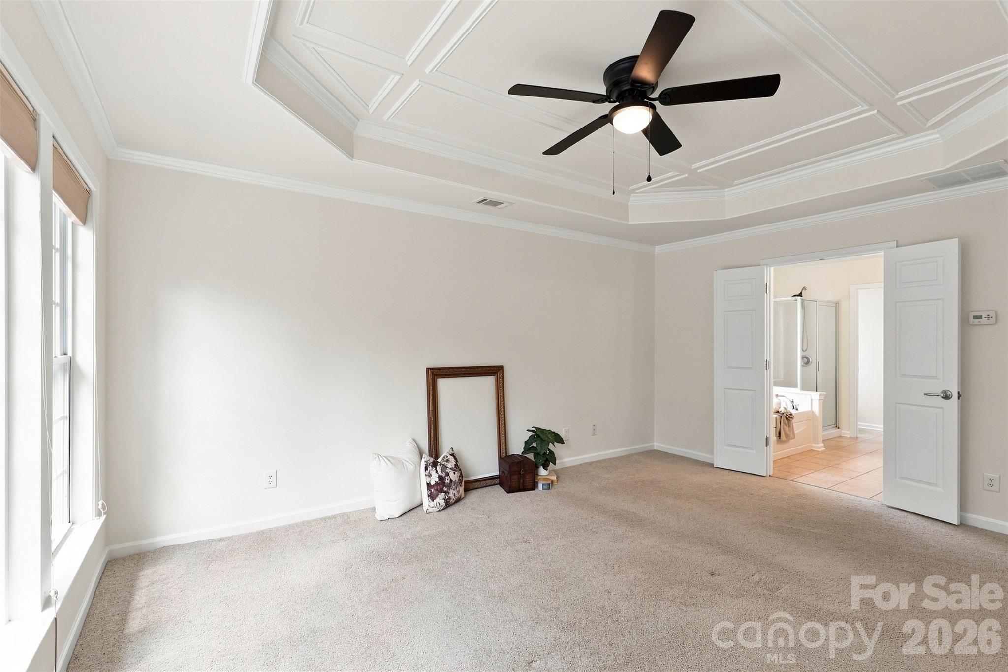 The primary bedroom easily accommodates king-size furnishings and a sitting area, with a ceiling fan and convenient direct access to the ensuite bath - 10345 Scotland Avenue, Indian Land