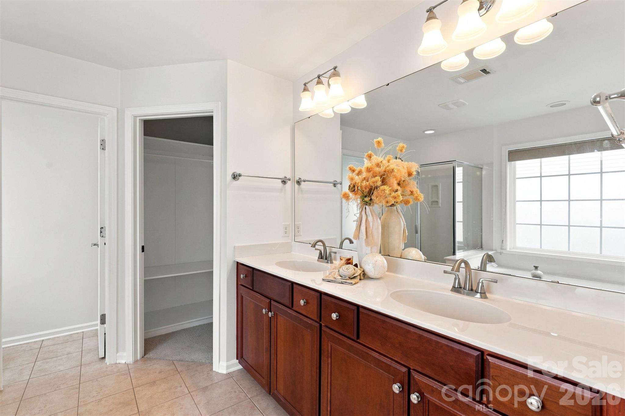 Primary bath features an extended dual-sink vanity with abundant counter space, ample storage, and a full-width mirror beneath updated lighting - 10345 Scotland Avenue, Indian Land