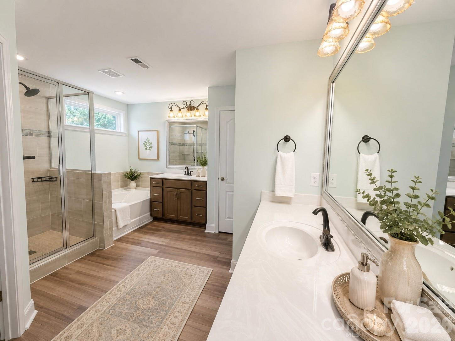 Primary Bathroom features dual vanities, upgraded faucets and lighting, upgraded flooring, standing shower features tile. Transom window above tub for natural llighting and privacy. Walk in Closet, linen closet and water closet included but not pictured. (photo has been virtually staged) - 1318 Poppy Way, Matthews