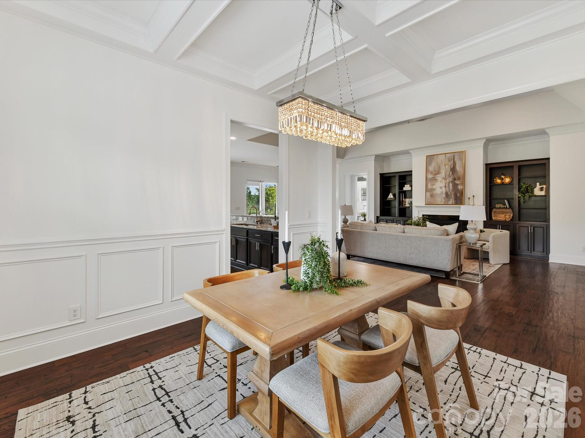 Elegant dining room features beautiful flooring, detailed wainscoting, a coffered ceiling and statement lighting with an open flow to the main living areas. - 13003 Riley Grace Lane, Cornelius