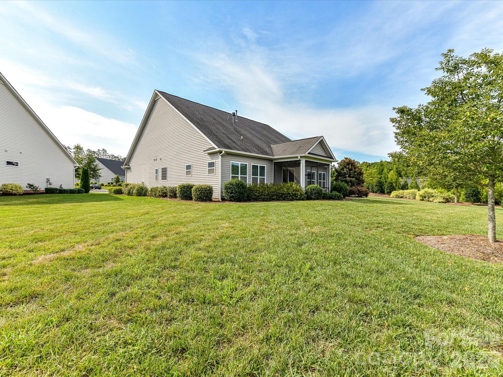 Spacious backyard features a large, level lawn with mature landscaping and a screened porch for enjoying outdoor living. - 13003 Riley Grace Lane, Cornelius