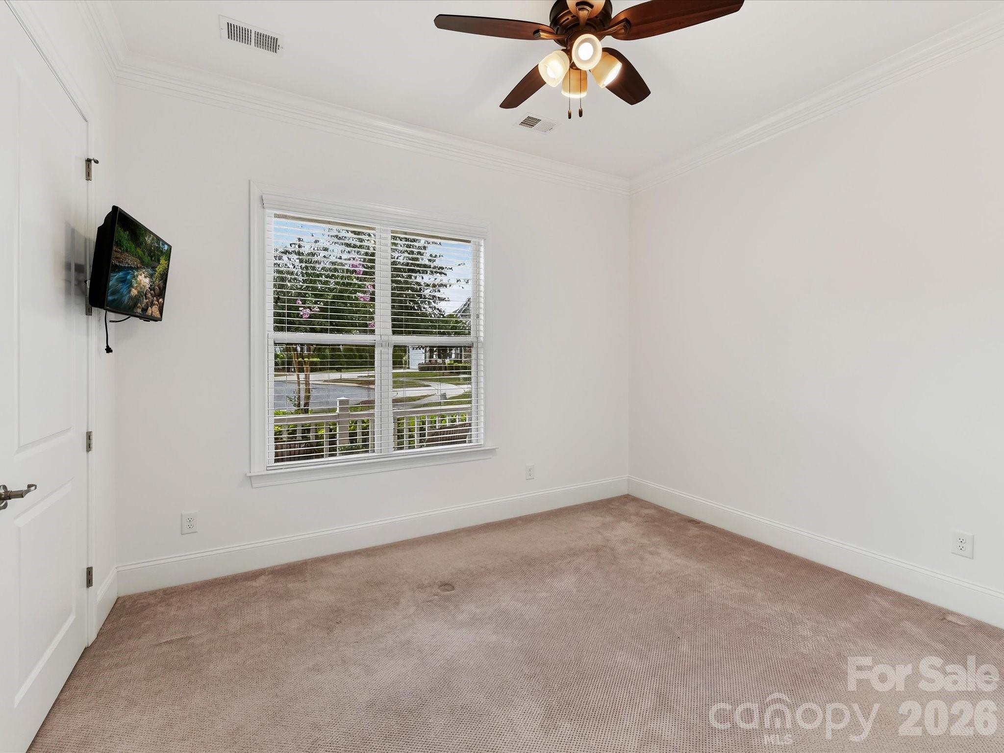 Main-level guest suite offers abundant natural light, crown molding, neutral carpeting, and flexibility for guests or additional living space. - 13003 Riley Grace Lane, Cornelius