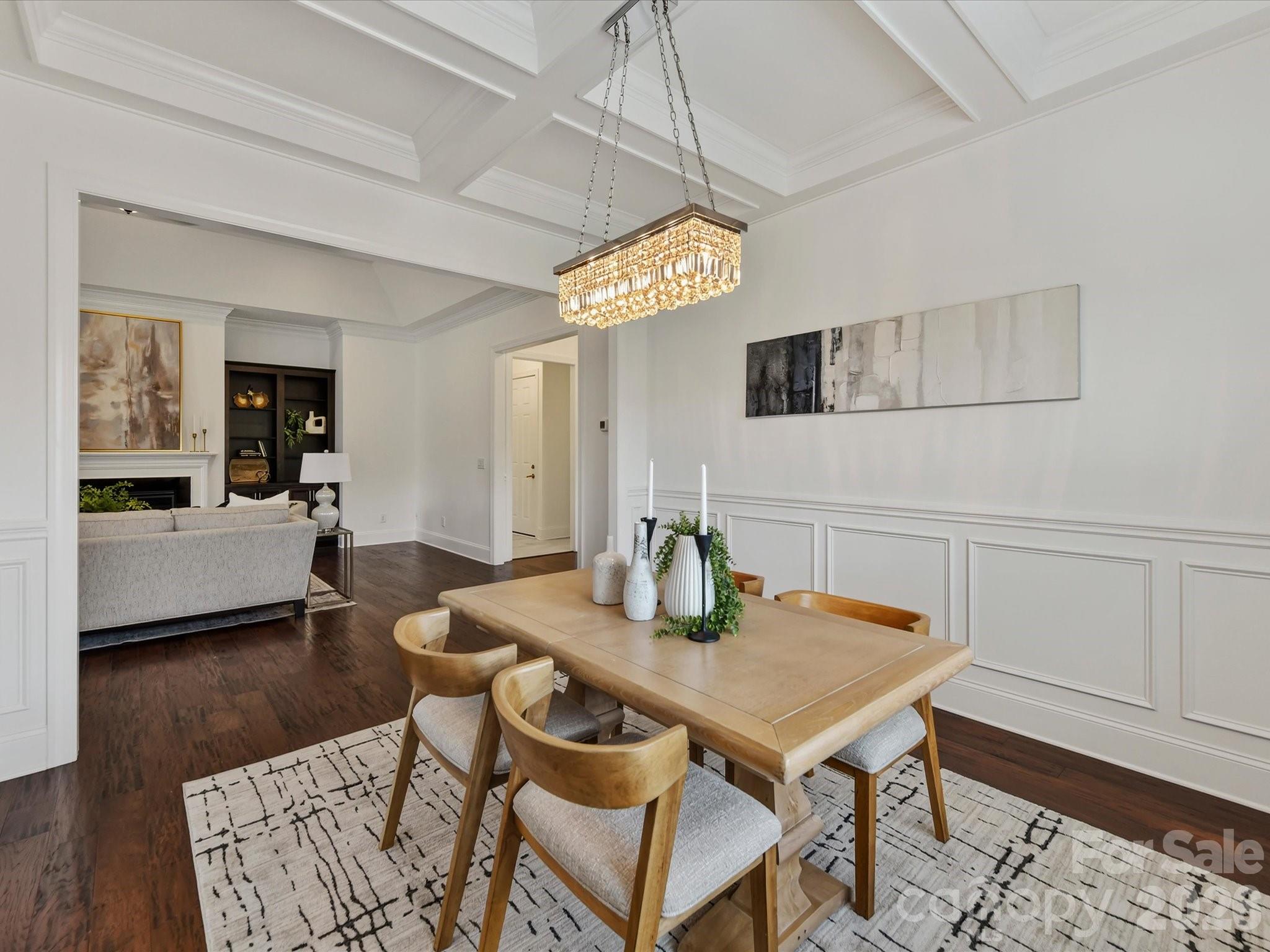 Elegant dining room features beautiful flooring, detailed wainscoting, a coffered ceiling and statement lighting with an open flow to the main living areas. - 13003 Riley Grace Lane, Cornelius