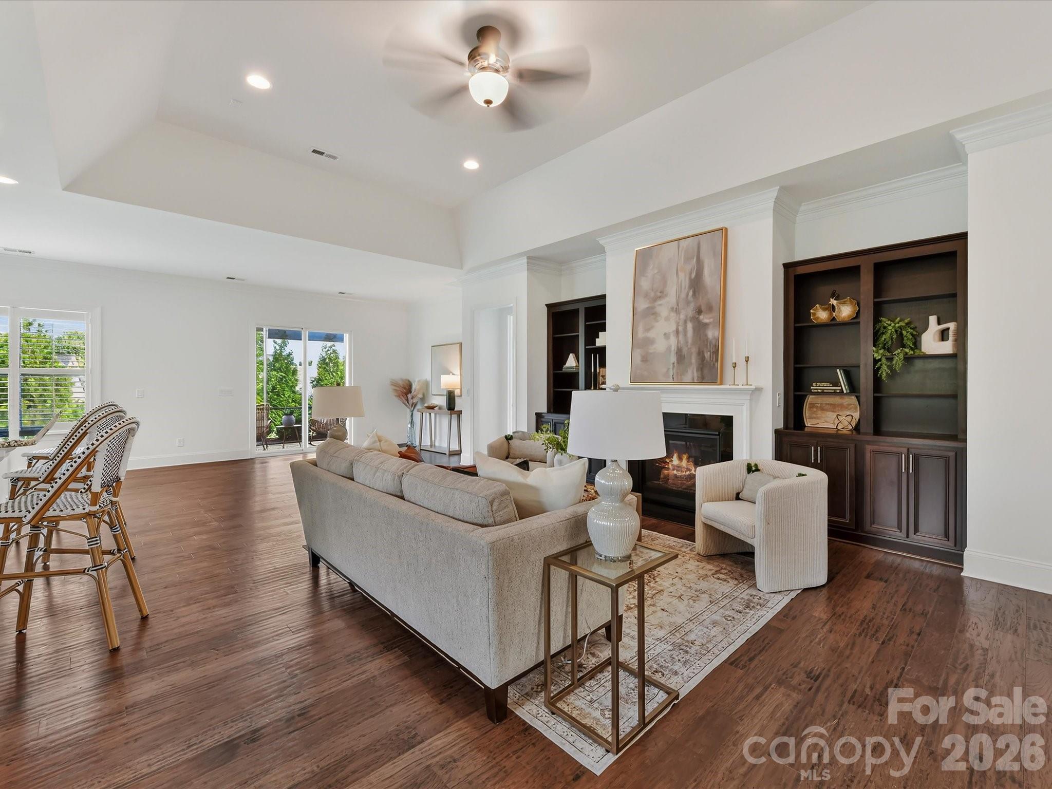 Spacious Great Room features a tray ceiling, cozy gas log fireplace flanked by built-in cabinetry, and an open layout ideal for everyday living and entertaining. - 13003 Riley Grace Lane, Cornelius