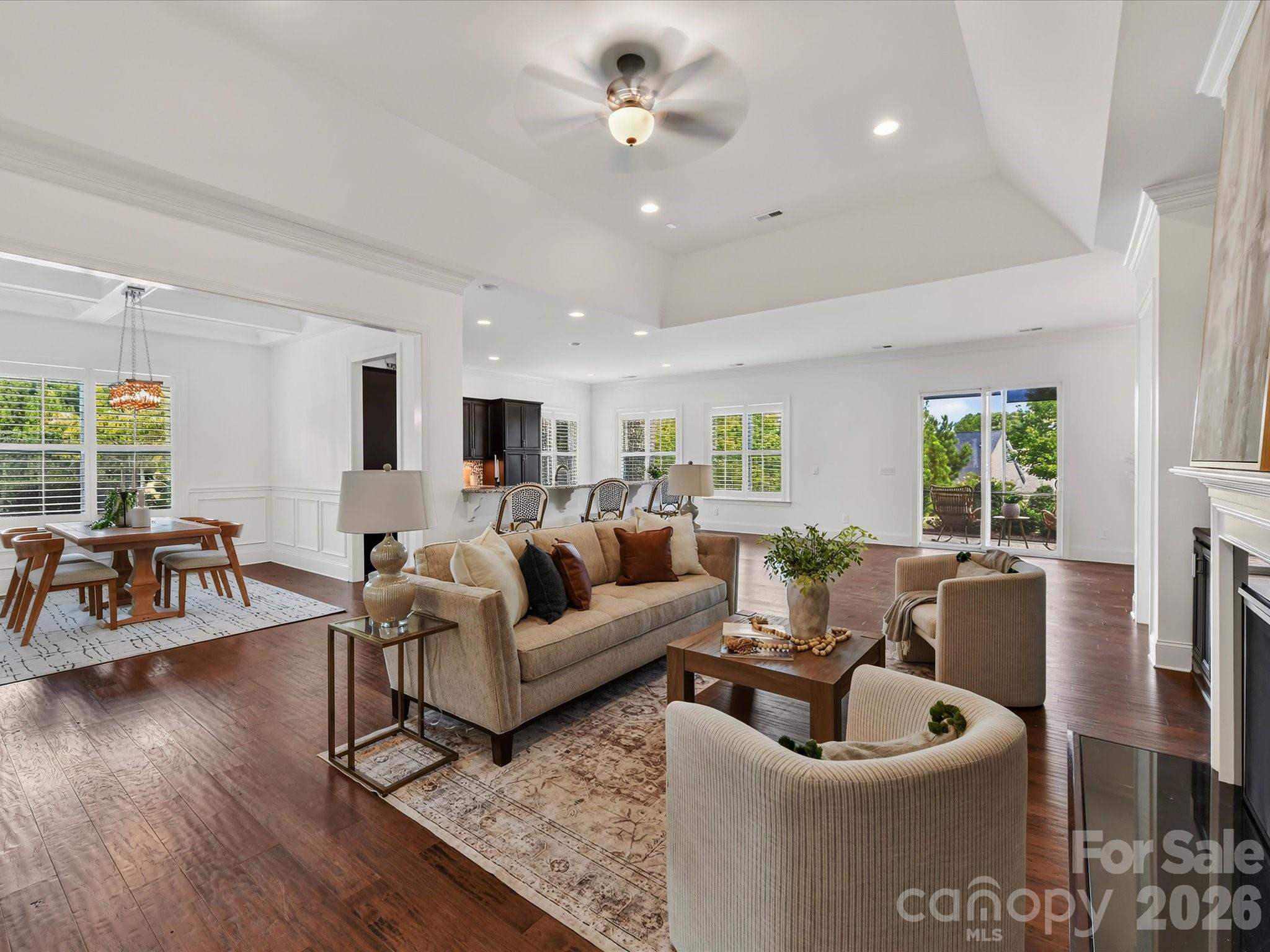 Spacious Great Room features a tray ceiling, cozy gas log fireplace flanked by built-in cabinetry, and an open layout ideal for everyday living and entertaining. - 13003 Riley Grace Lane, Cornelius