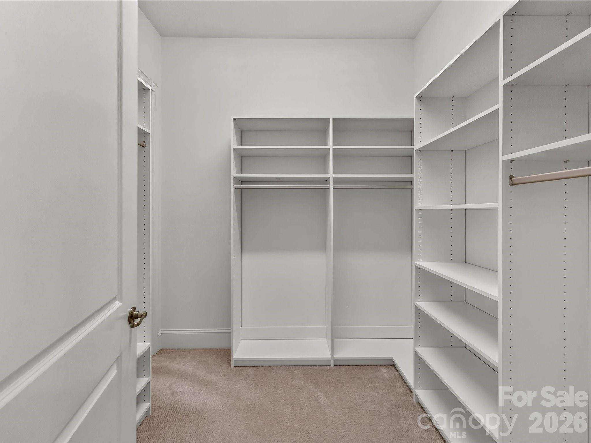 Generously sized primary walk-in closet features custom built-in shelving and hanging space for exceptional storage and organization. - 13003 Riley Grace Lane, Cornelius