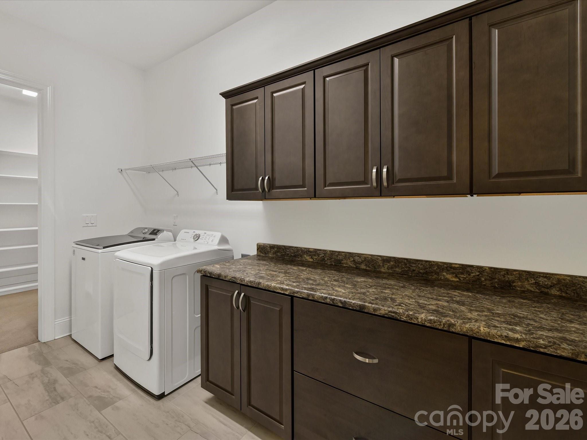 Spacious laundry room offers abundant cabinetry, generous counter space, and additional shelving for convenient storage and organization. - 13003 Riley Grace Lane, Cornelius