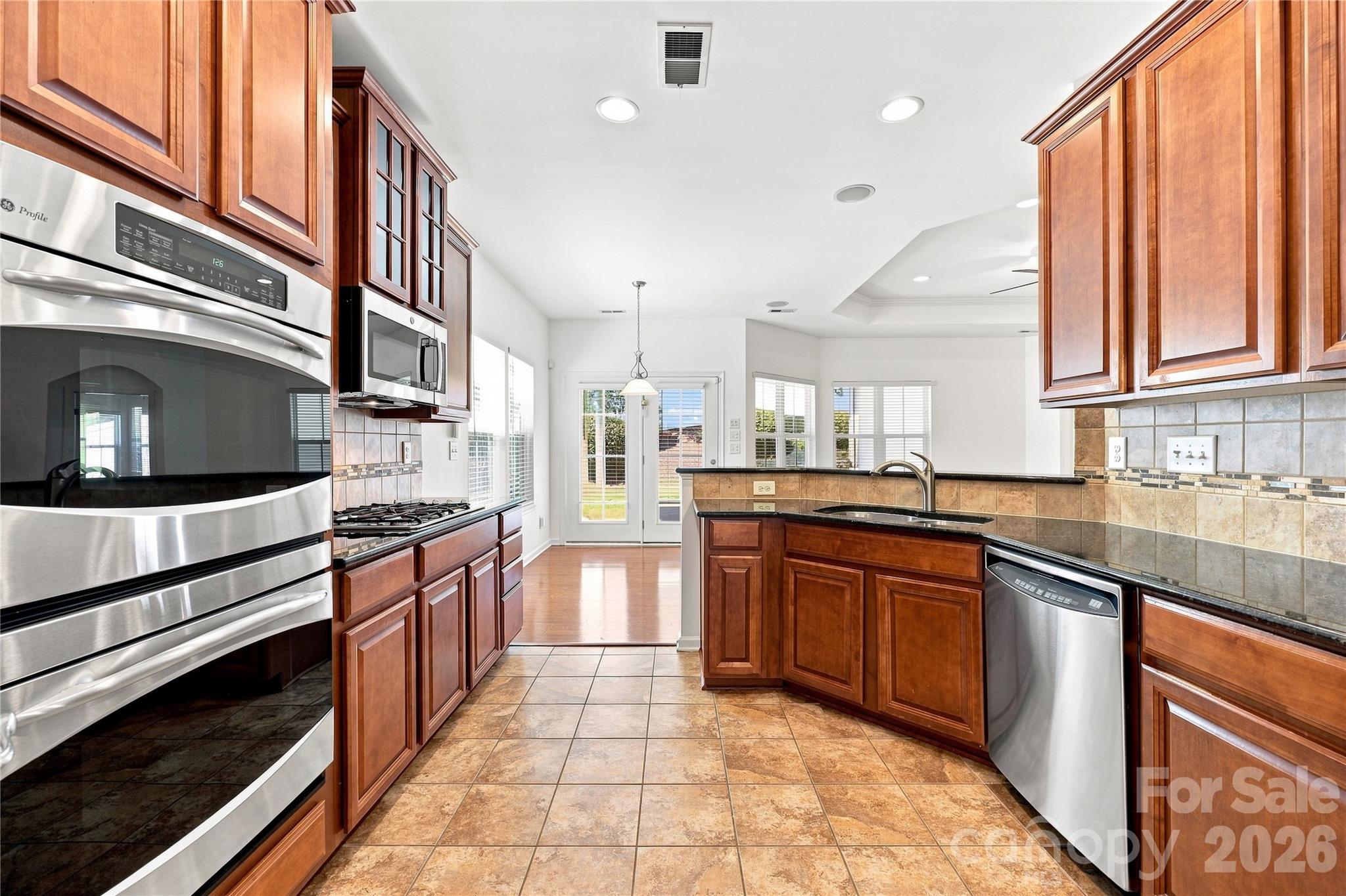 Kitchen with 32 in. cabinets, stainless steel appliances, gas stove top, double ovens, microwave, granite counters, tile backsplash and newer refrigerator - 593 Harrison Drive NW, Concord