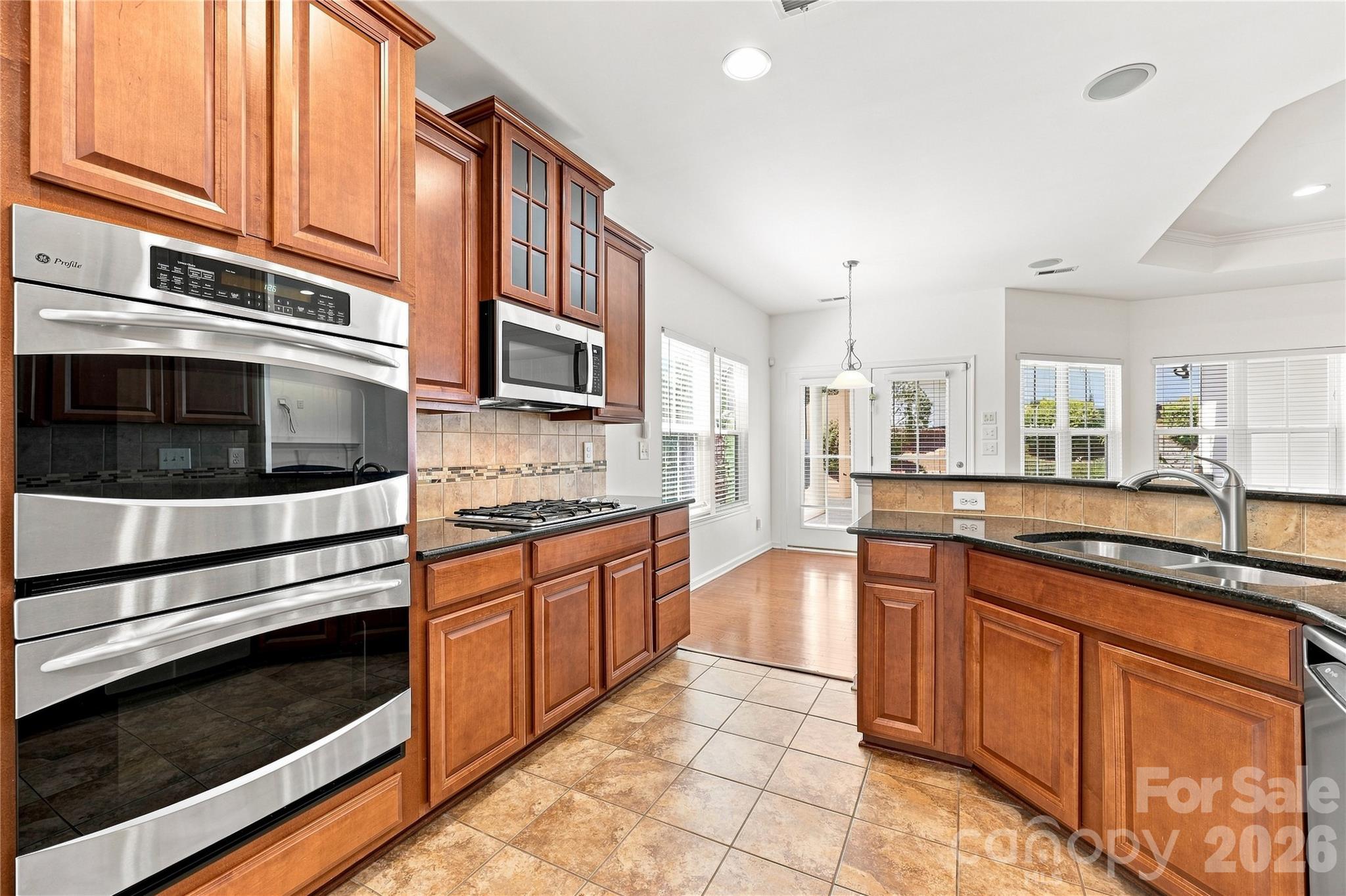Kitchen with 32 in. cabinets, stainless steel appliances, gas stove top, double ovens, microwave, granite counters, tile backsplash and newer refrigerator - 593 Harrison Drive NW, Concord
