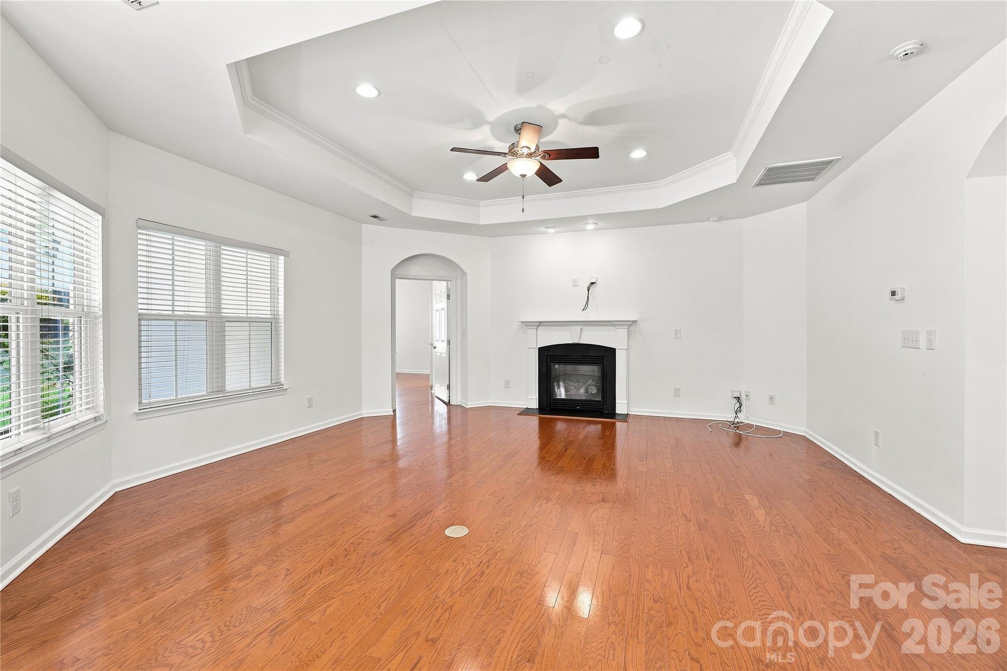 Spacious family room with gas fireplace, trey ceiling with fan - Door in back leads to primary bedroom suite - 593 Harrison Drive NW, Concord