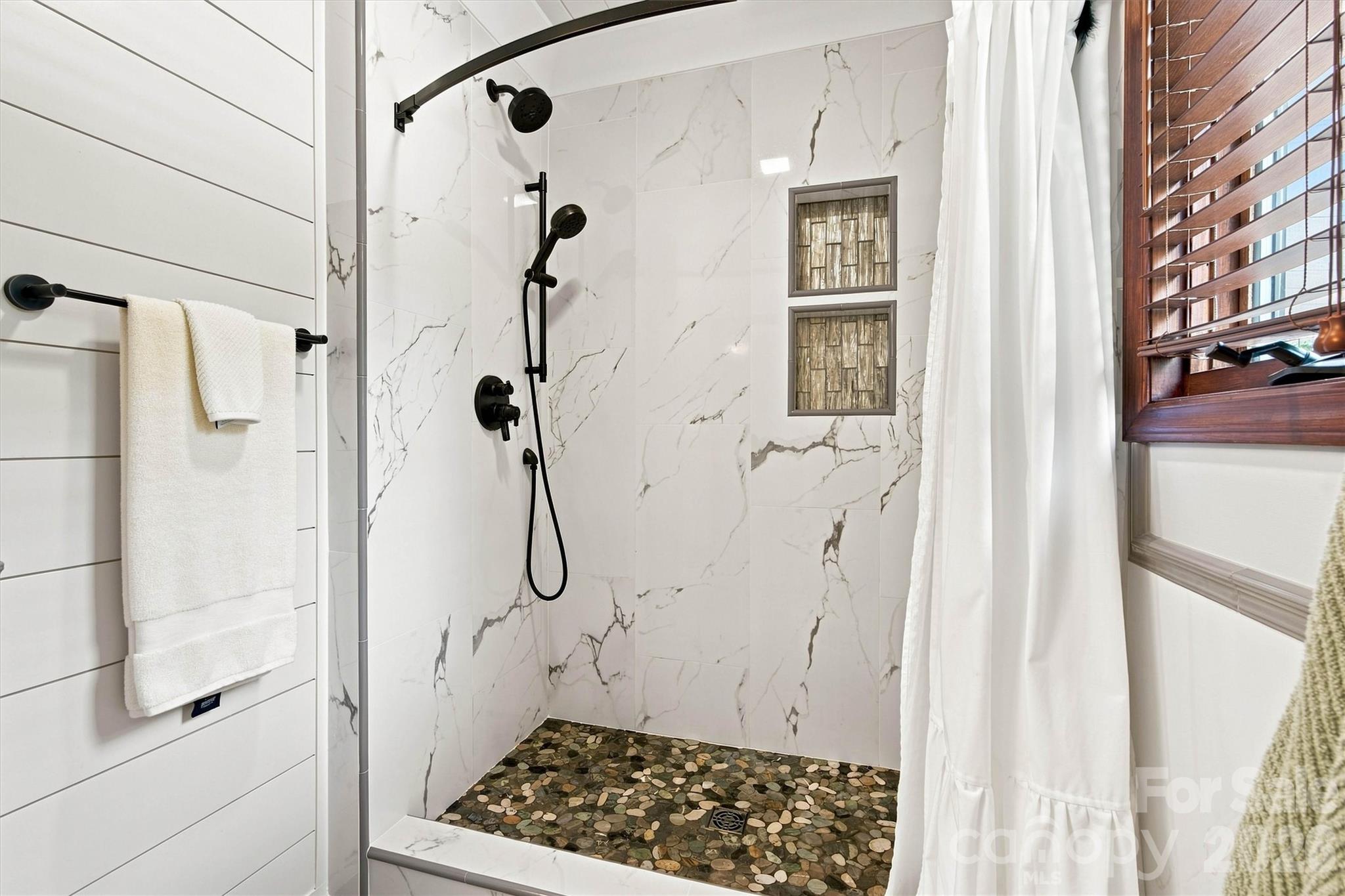 Beautiful wood accent wall and this beautiful custom tile shower complete the Primary Bath - 3867 Angie Drive, Denver