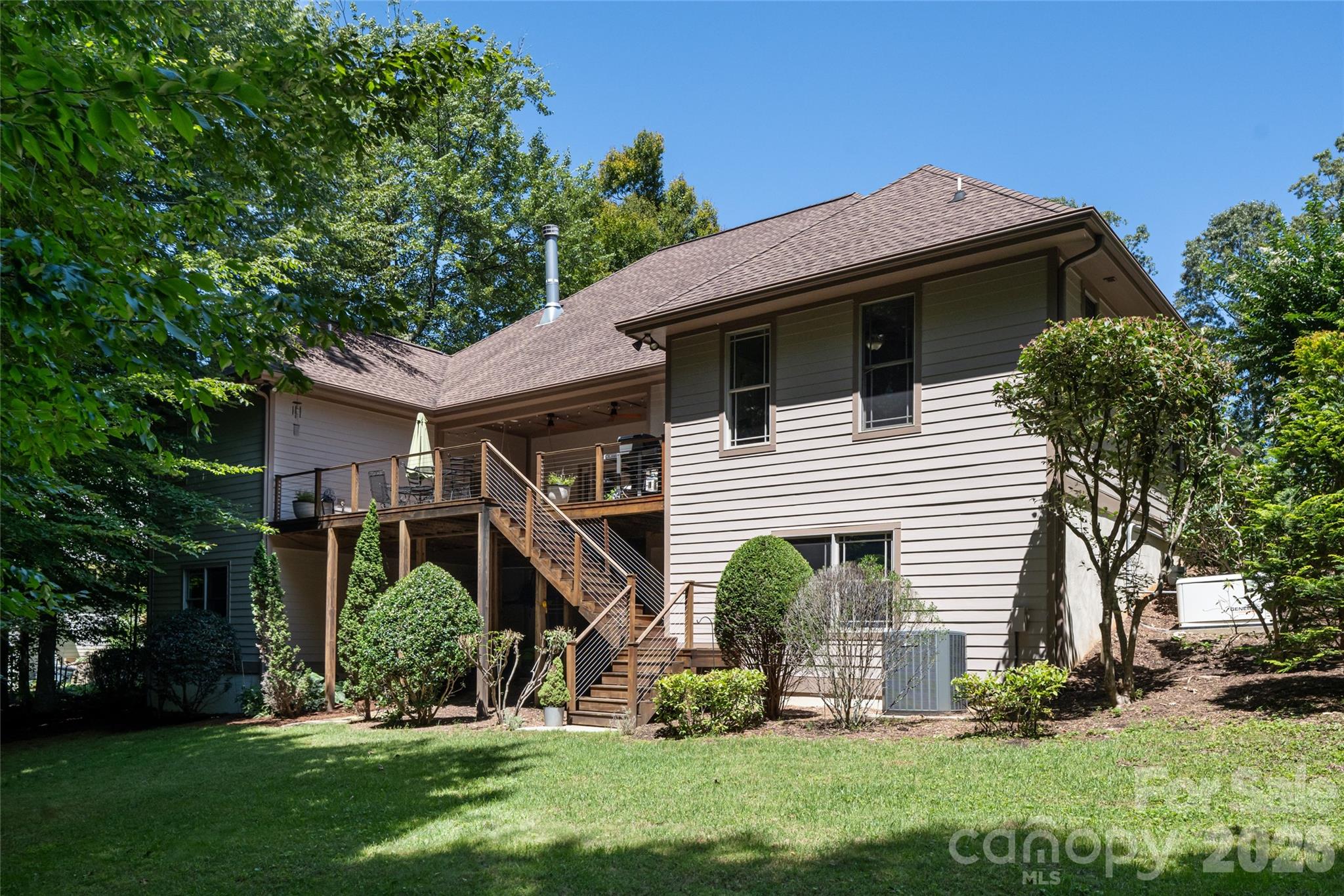 A large, private back yard with firepit, grass and shade, and upper porch with Ipe flooring and a hanging porch bed, partially covered, and basement access from under covered lower area with concrete pad. - 170 Cape Martin Circle, Hendersonville