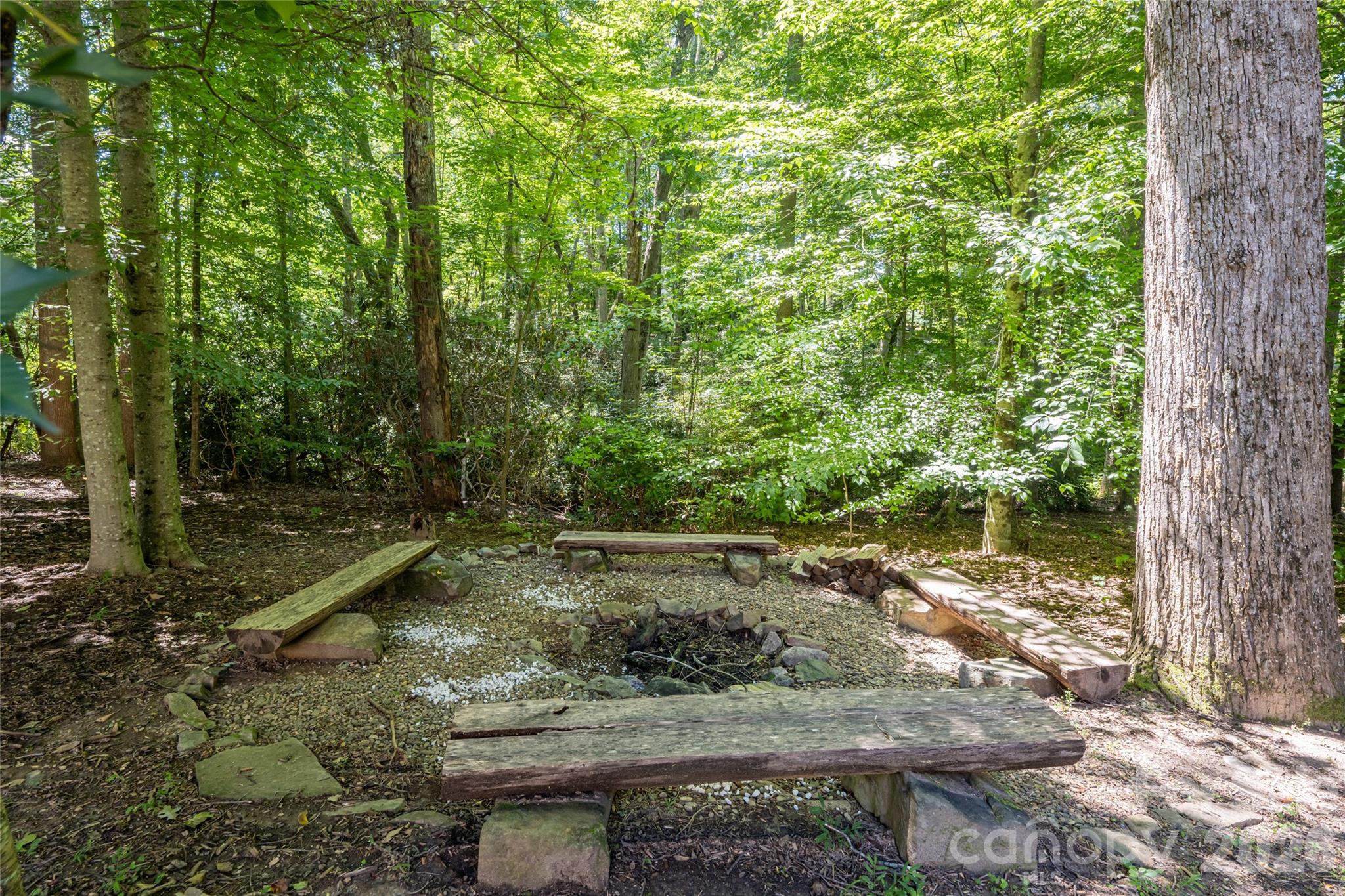 A large, private back yard with firepit, grass and shade, and upper porch with Ipe flooring and a hanging porch bed, partially covered, and basement access from under covered lower area with concrete pad. - 170 Cape Martin Circle, Hendersonville