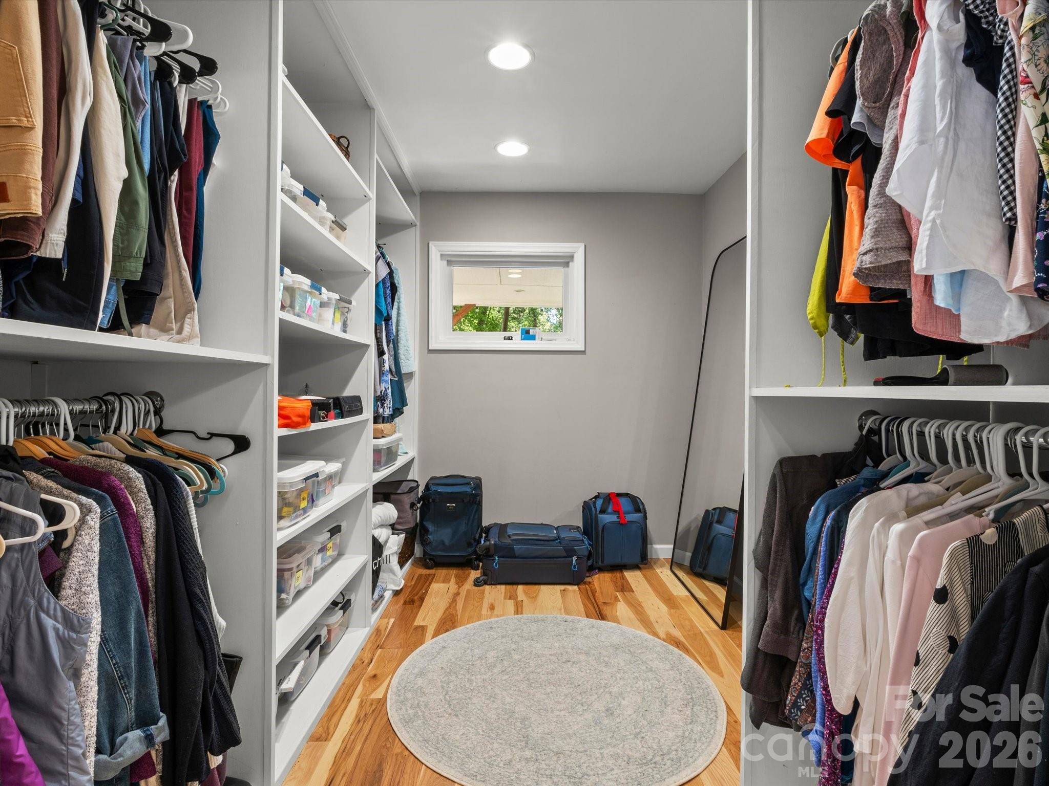 The oversized walk-in closet is beautifully appointed with bright lighting, natural light from the window, and more hardwood floors - 110 Aurora Drive, Asheville