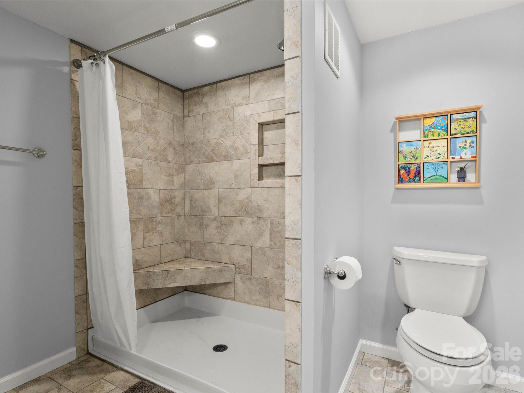 The walk-in tiled shower also features a wall niche and corner bench - 110 Aurora Drive, Asheville