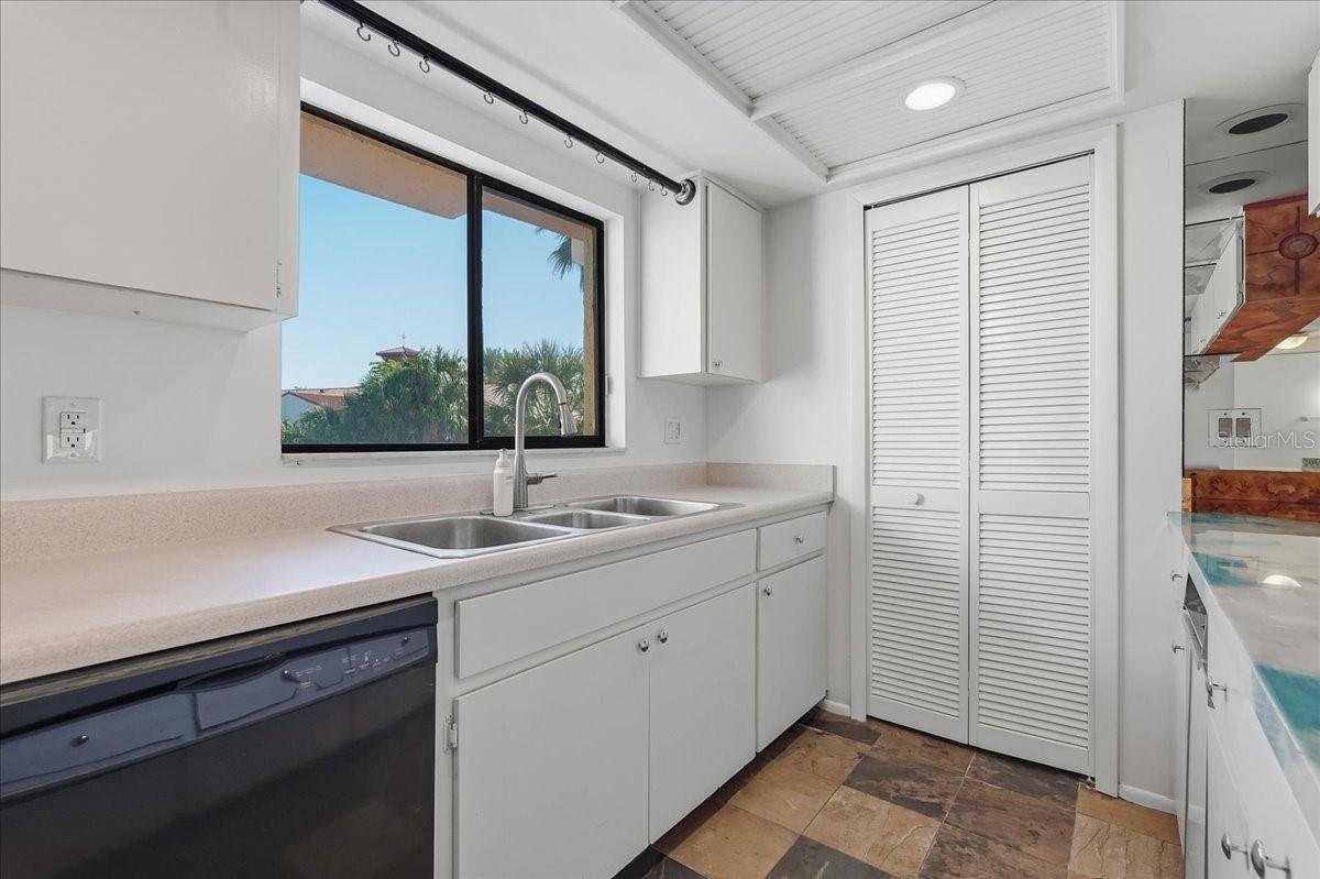 Smart storage solutions: Equipped with crisp white upper and lower cabinetry, a deep triple-basin sink, a dedicated pantry closet, and integrated appliances - 240 WINDWARD PSGE #702, CLEARWATER