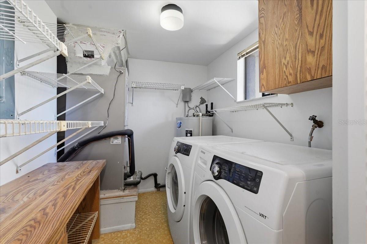 Comprehensive Multi-Purpose Utility Room: Connected to the Kitchen, features high-capacity laundry appliances, central mechanical systems (HVAC handler and water heater), and generous built-in storage racks to keep your home perfectly organized. - 240 WINDWARD PSGE #702, CLEARWATER