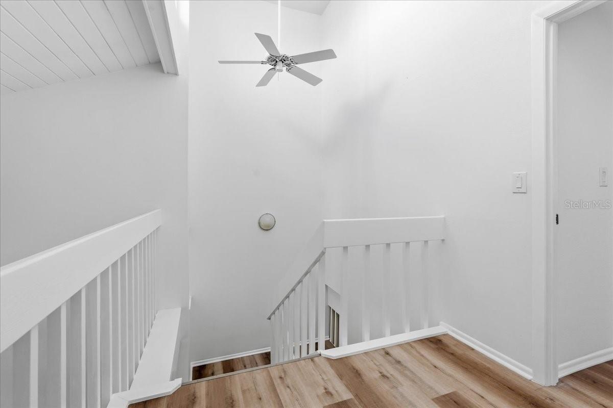 The staircase and landing offer a beautiful overlook of the open-concept Great Room, leading directly to two spacious Primary Suites - 240 WINDWARD PSGE #702, CLEARWATER