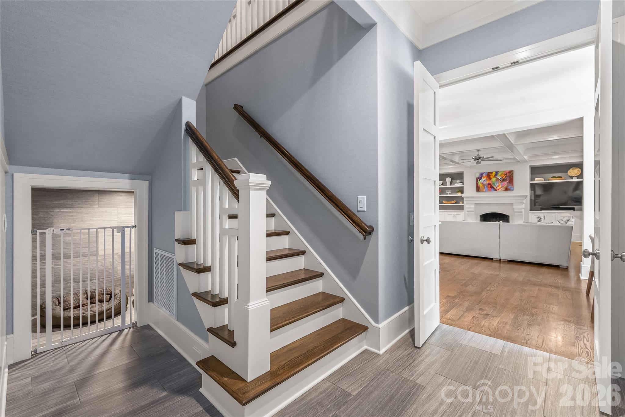 Transition from the main living area to the resource room and wide wooden stairs to the second story. Note the Harry Potter room for the four-legged family members - 2800 Wintergreen Drive, Charlotte