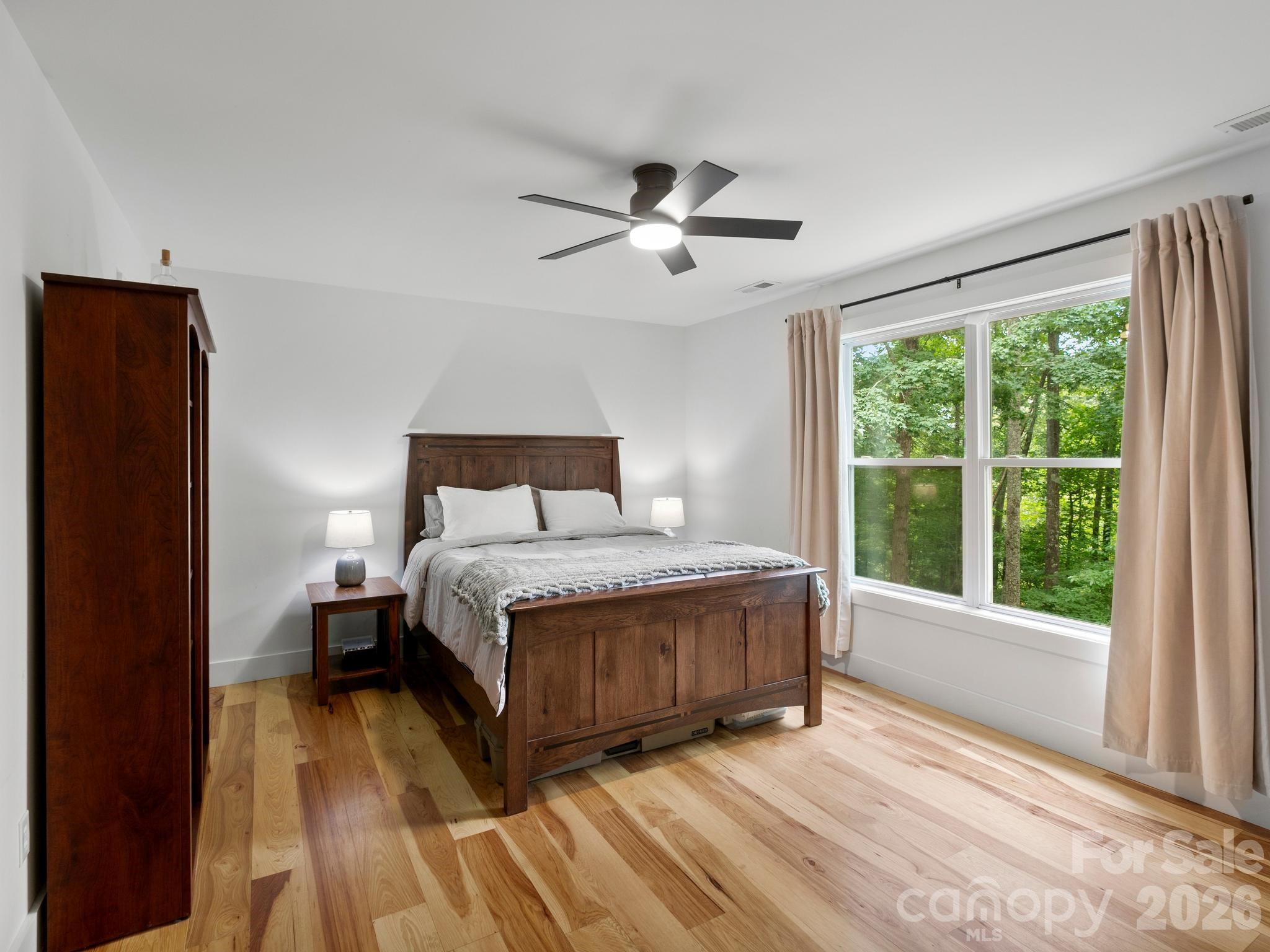 Primary bedroom with windows facing southwest, catching warm sunset light. - 41 Bear Trail, Fairview