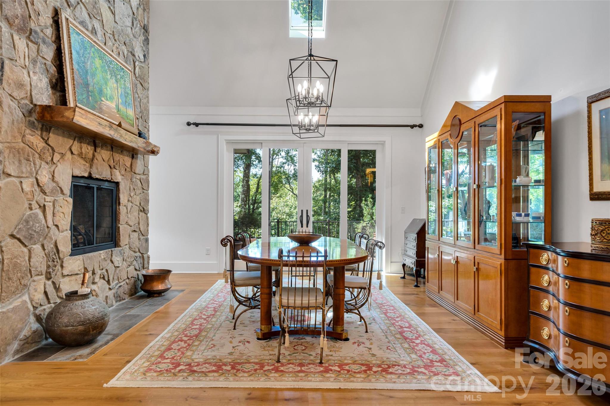 Open floorplan to the dining area with double sided fireplace and two chandeliers - 442 Autumn Sky Drive, Hendersonville