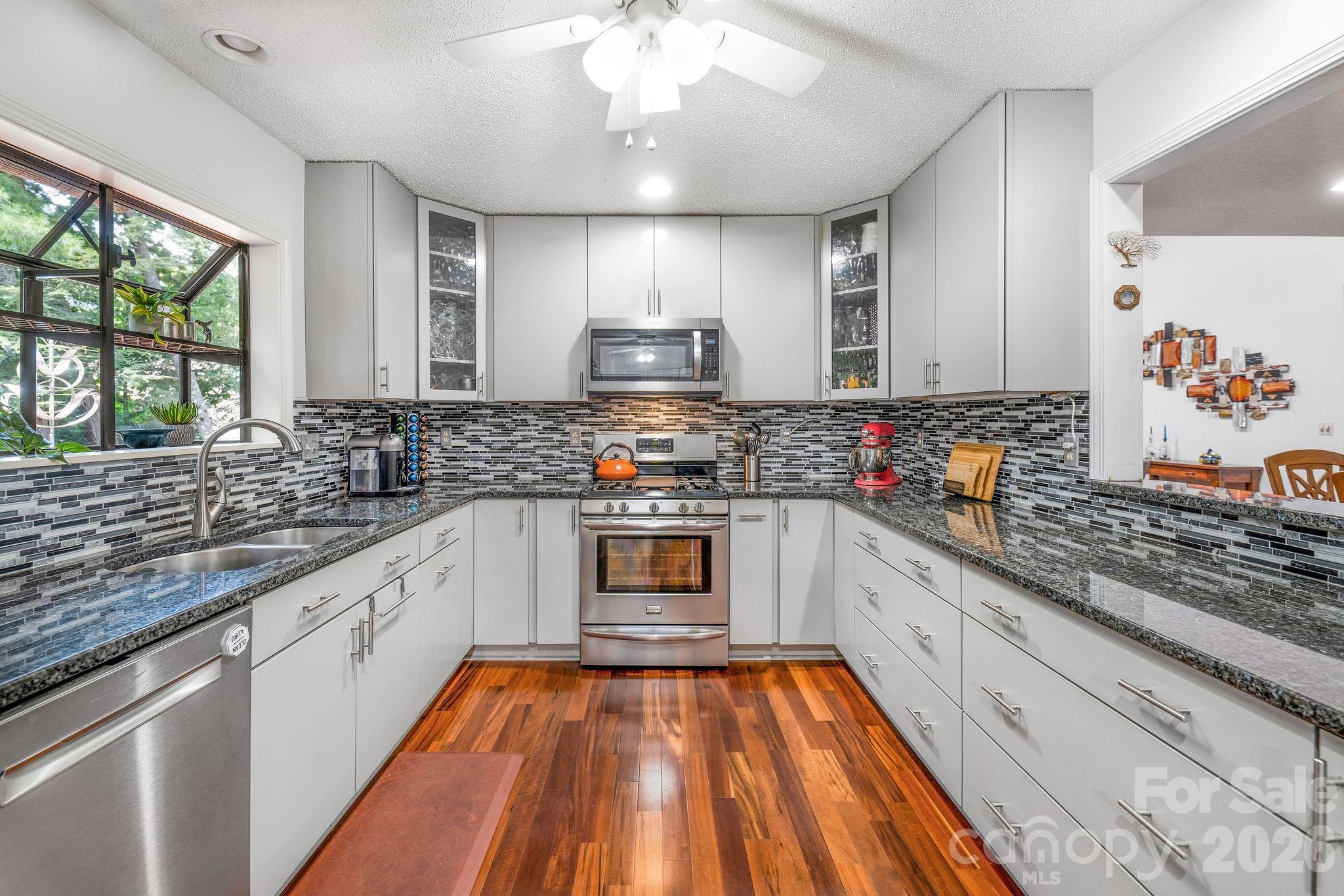 The contemporary kitchen features a gas range, stainless steel appliances, and tons of storage! - 31 Hillcreek Drive, Asheville