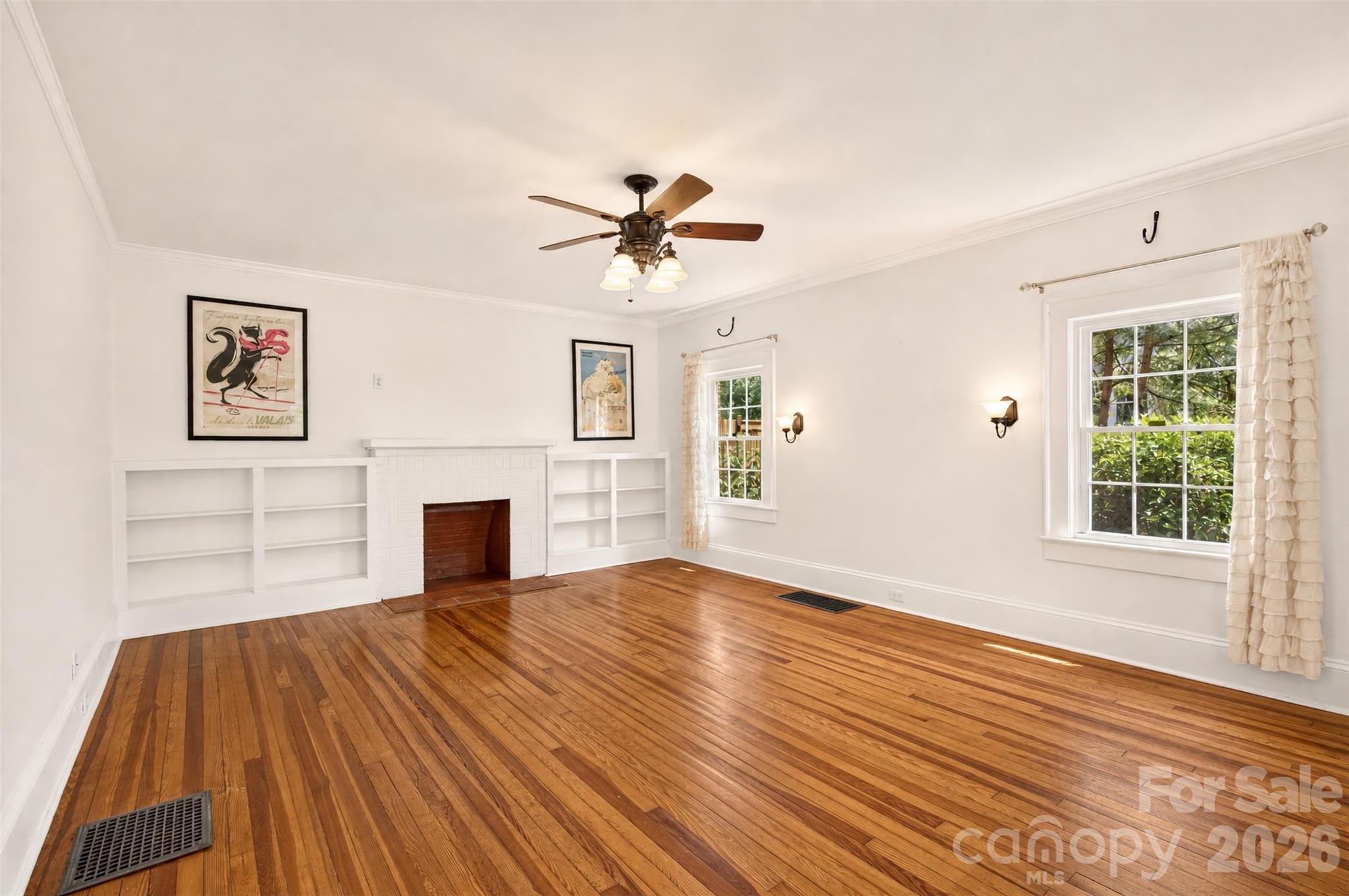 Hardwood floors, built-in shelving, crown molding, and plenty of natural light add character to the spacious living room. The fireplace is decorative/non-functional. - 638 Carolina Avenue, Gastonia