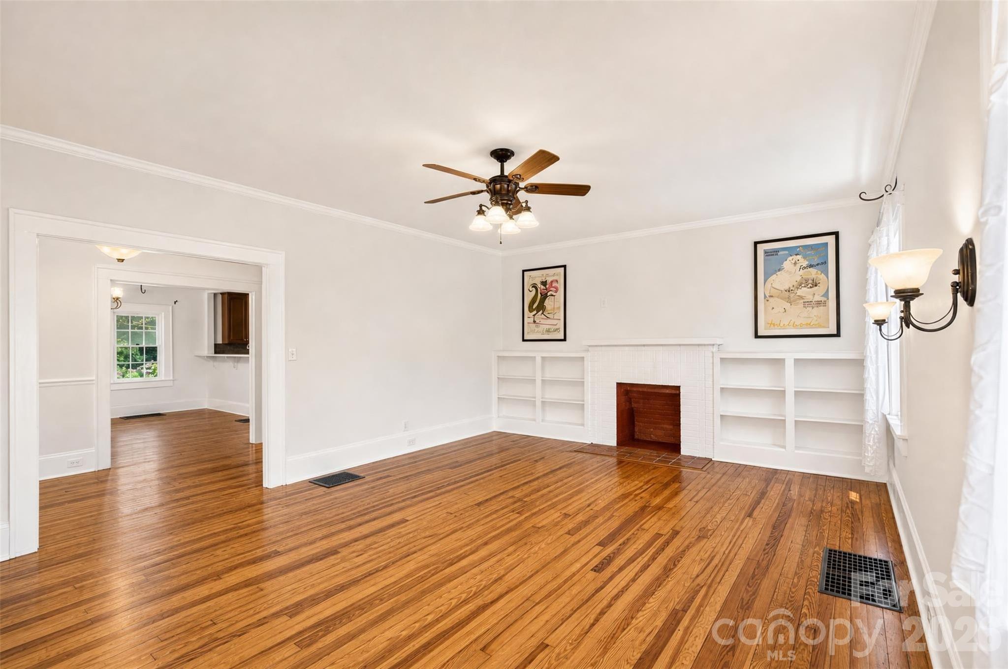 Another view of the living room highlights the classic wall sconce lighting and generous floor space, with a beautiful connection across to the dining area and kitchen. - 638 Carolina Avenue, Gastonia