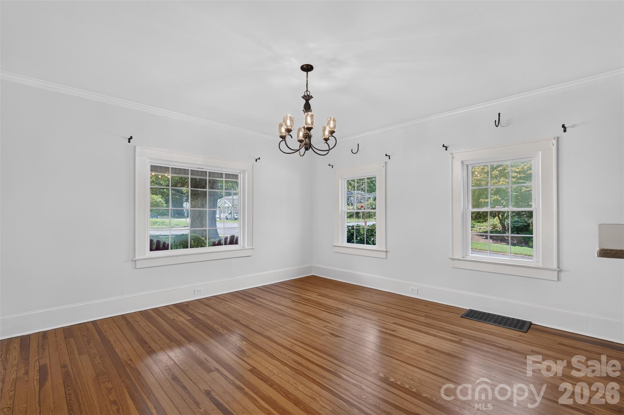 Another view of the dining room, where three large windows bring in abundant natural light. Thoughtfully placed plant hooks provide options for adding greenery above the windows. - 638 Carolina Avenue, Gastonia