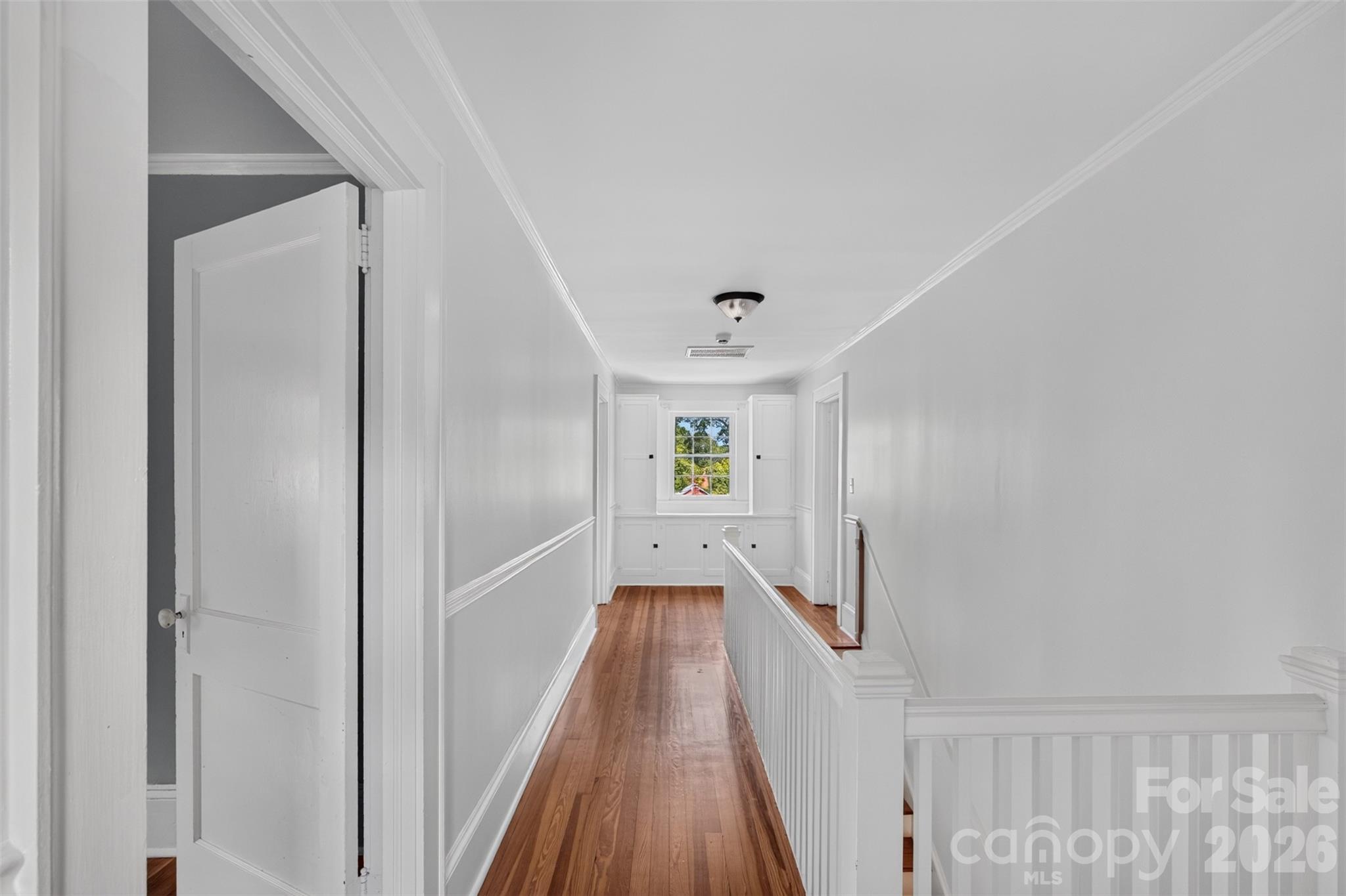 The upstairs landing continues the hardwood floors and classic millwork with built-in cabinetry surrounding a window at the end of the hall. - 638 Carolina Avenue, Gastonia