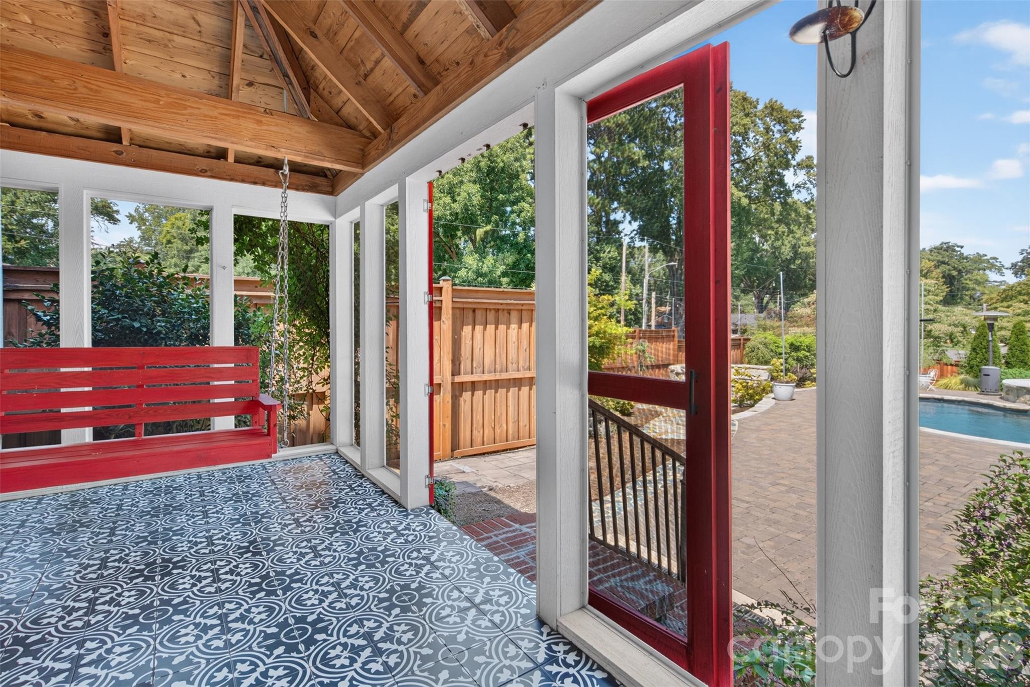 Screened porch with a vaulted wood ceiling, exposed beams, decorative flooring, and views into the backyard retreat. - 638 Carolina Avenue, Gastonia