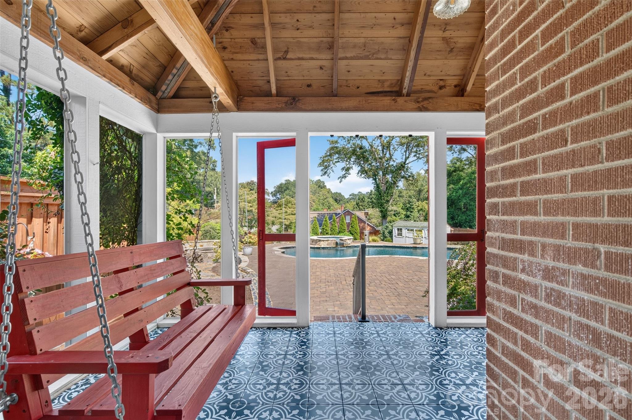 A porch swing, soaring wood ceiling, and a direct view of the pool set the stage for the outdoor living spaces beyond. - 638 Carolina Avenue, Gastonia