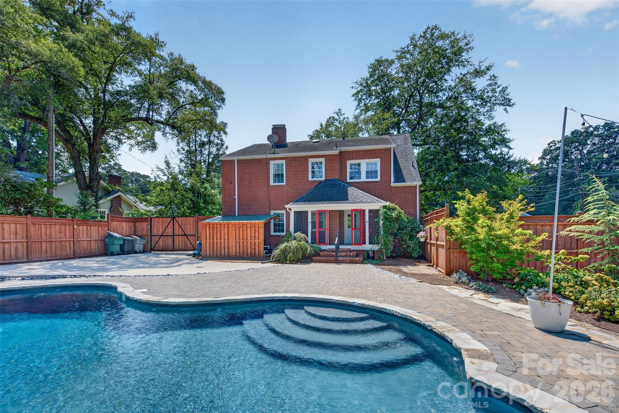An all-season backyard oasis featuring heated pool, hot tub, expansive paver patio, and multiple spaces to relax, gather, and entertain. - 638 Carolina Avenue, Gastonia