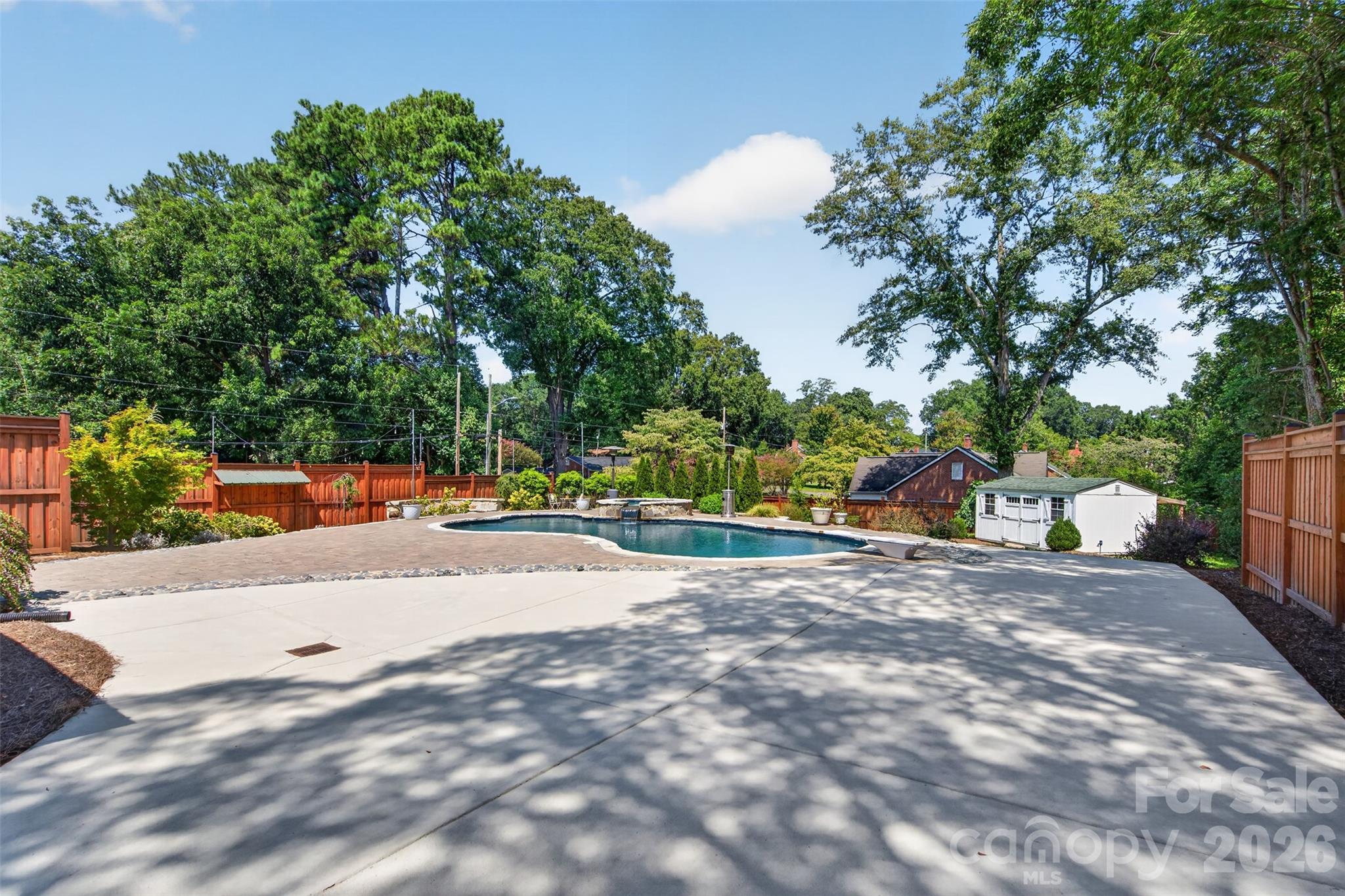 Elevated view across the backyard showcases the impressive scale of the outdoor retreat with expansive hardscaping, the heated pool and spa, mature trees, and landscaped grounds. - 638 Carolina Avenue, Gastonia