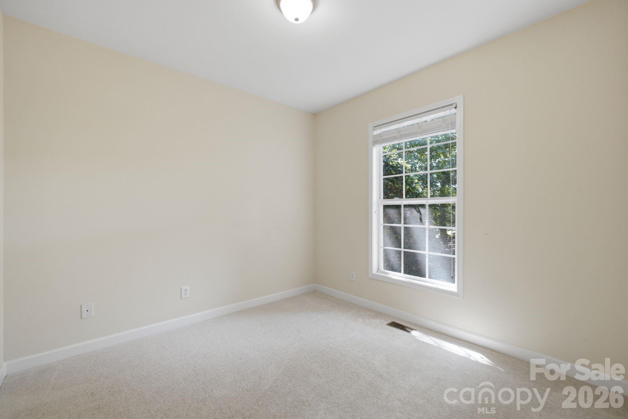 Bright, spacious second bedroom featuring large windows, abundant natural light, plush carpet, generous closet space, and neutral paint. - 14724 Beatties Ford Road, Huntersville
