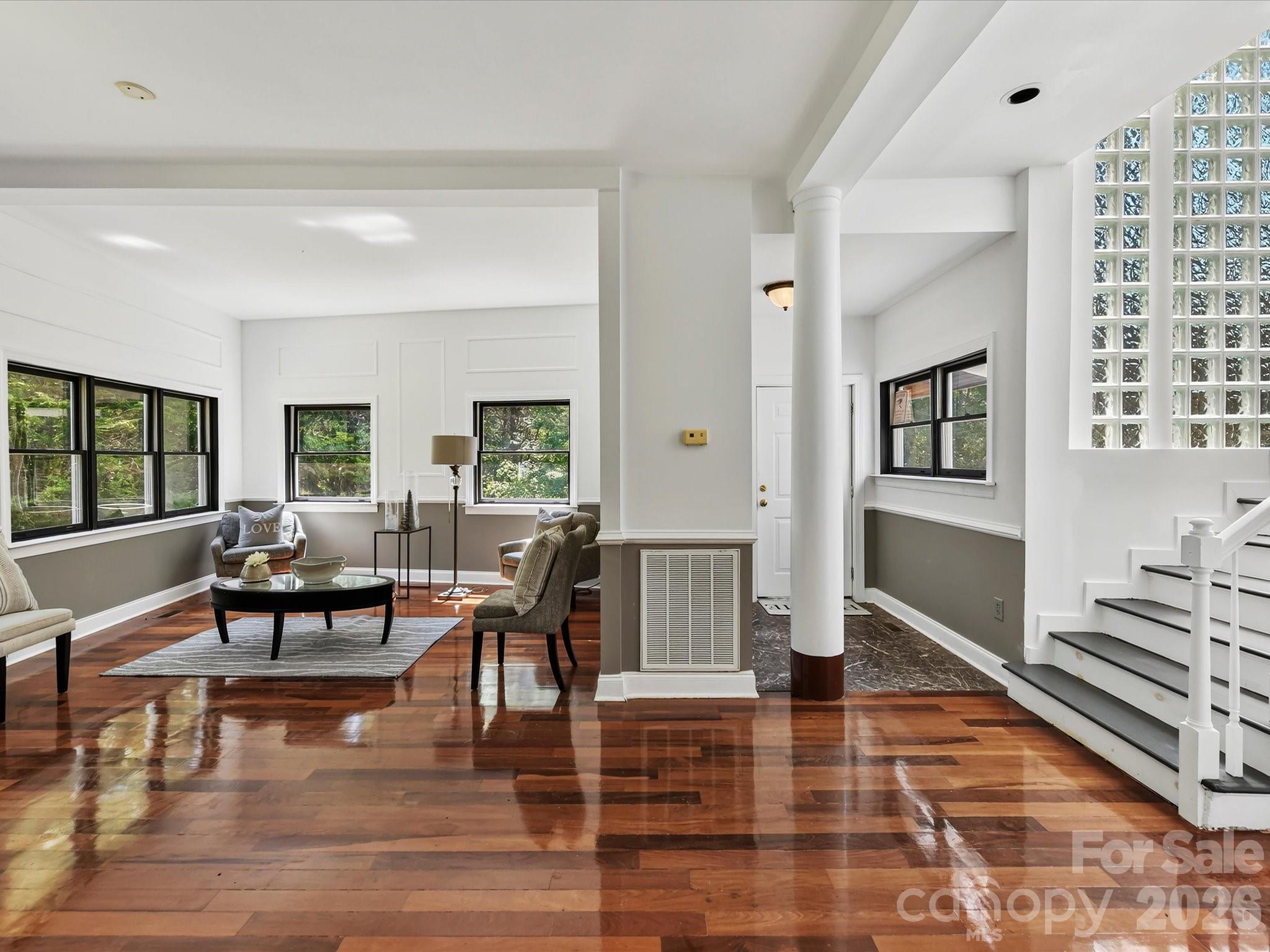 An open, light-filled interior welcomes you with gleaming Brazilian hardwood floors, abundant windows, architectural details, and a dramatic glass-block staircase. - 9821 Harvest Lane, Davidson