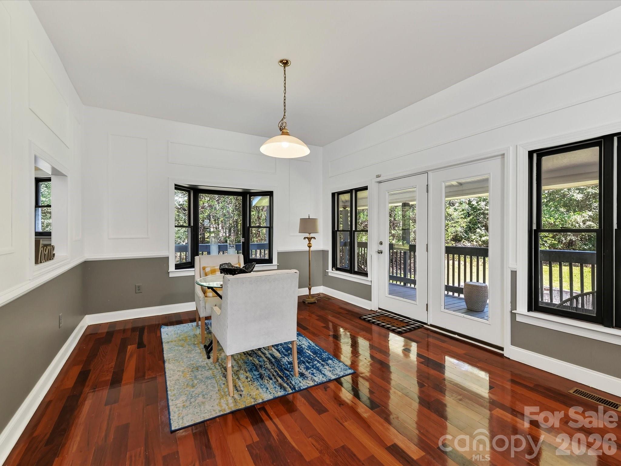 Bright dining area with Brazilian hardwood floors, walls of windows, and direct access to the covered outdoor living space overlooking the private Davidson acreage. - 9821 Harvest Lane, Davidson