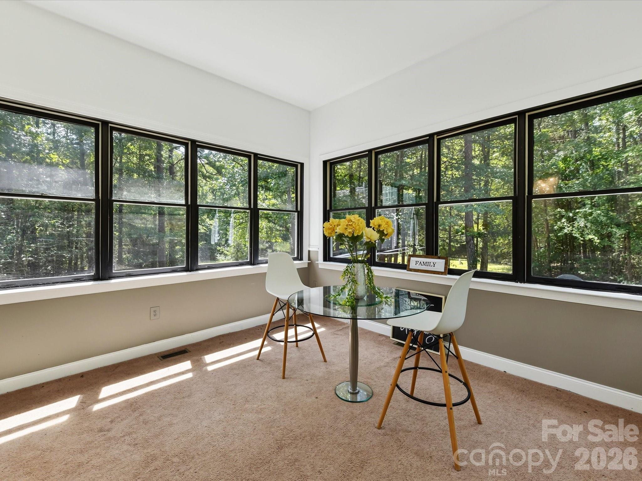 Light-filled sunroom surrounded by oversized windows showcases tranquil wooded views and the privacy of this expansive Davidson property. - 9821 Harvest Lane, Davidson