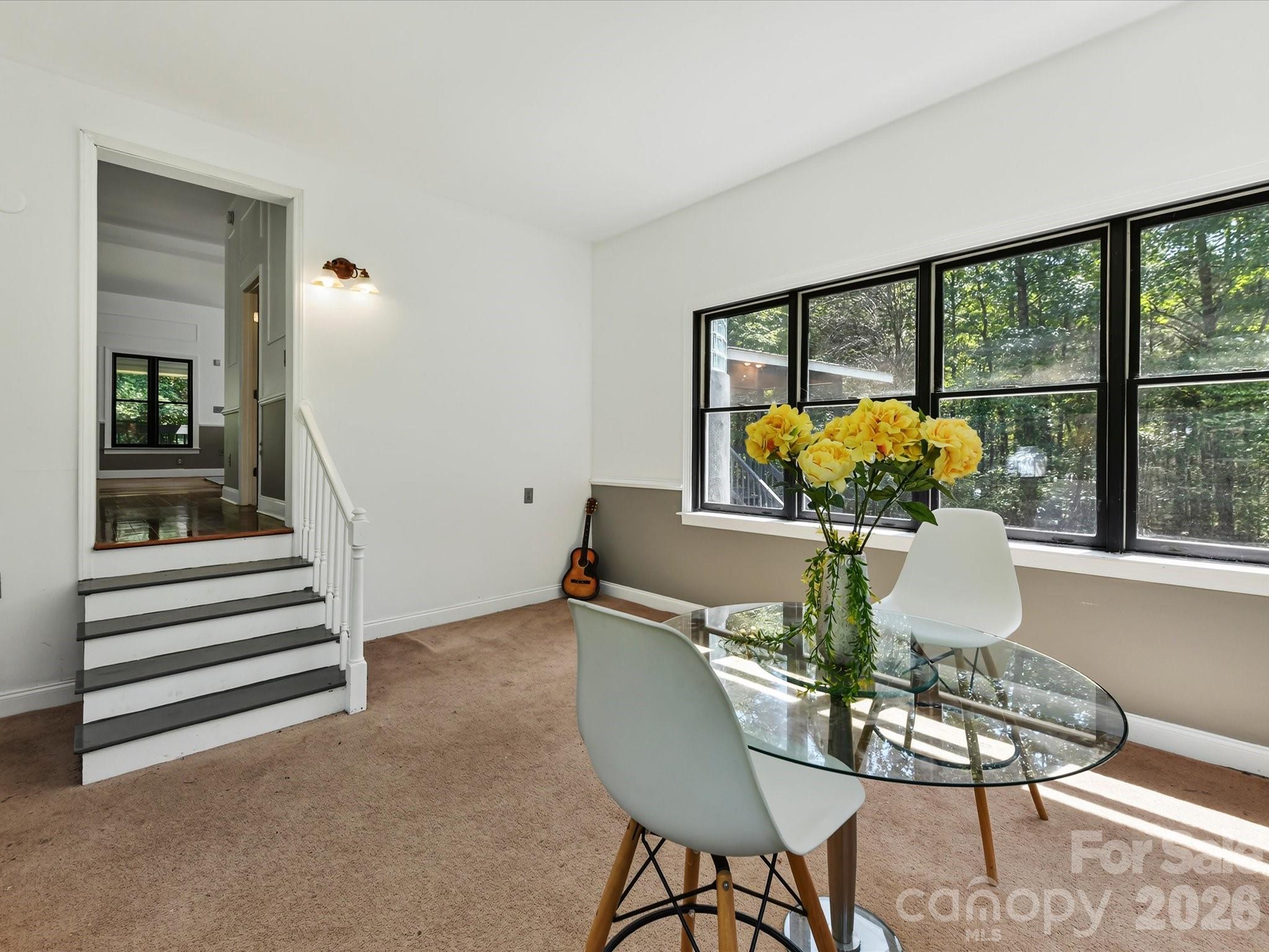 Versatile sunroom or flex space offers abundant natural light, panoramic wooded views, and endless possibilities for dining, office, or additional living space. - 9821 Harvest Lane, Davidson