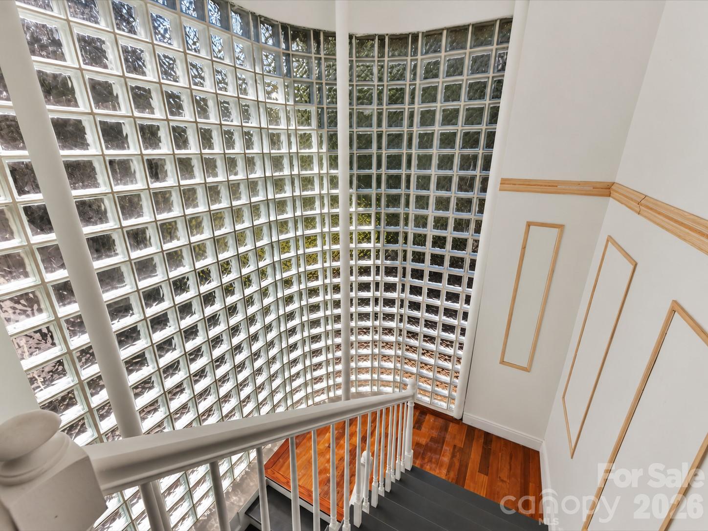 Dramatic curved floor-to-ceiling glass block wall floods the staircase with natural light, creating a distinctive architectural focal point. - 9821 Harvest Lane, Davidson