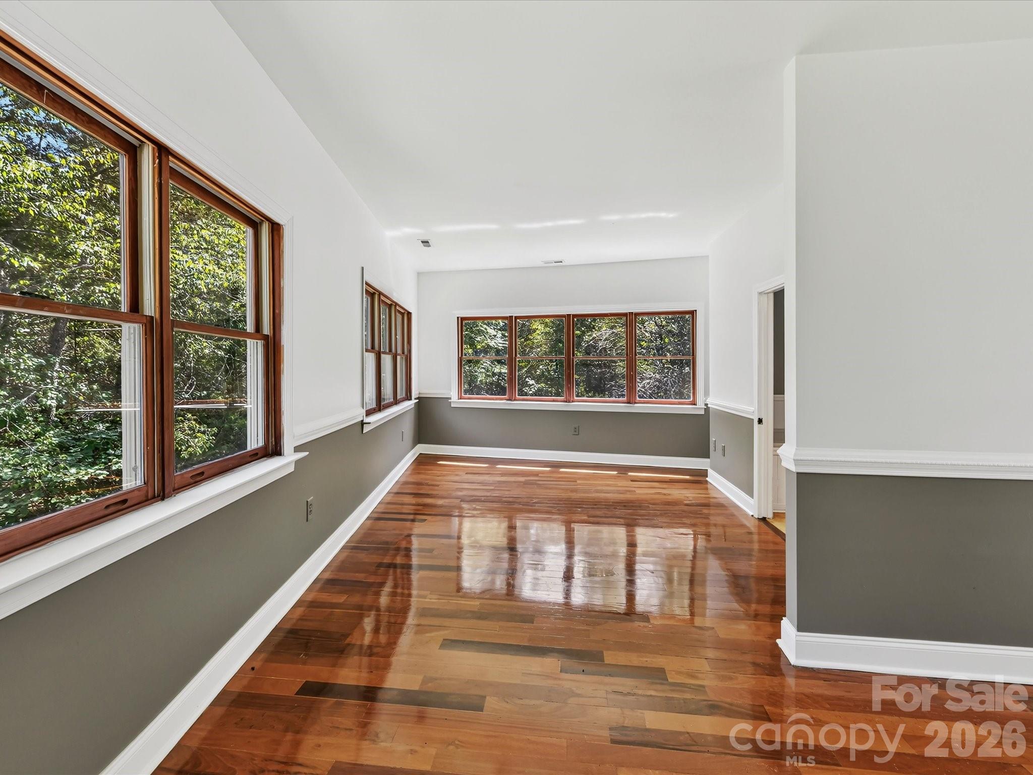 The bright primary bedroom offers beautiful Brazilian hardwood flooring, expansive windows, and generous space for a comfortable bedroom retreat. - 9821 Harvest Lane, Davidson