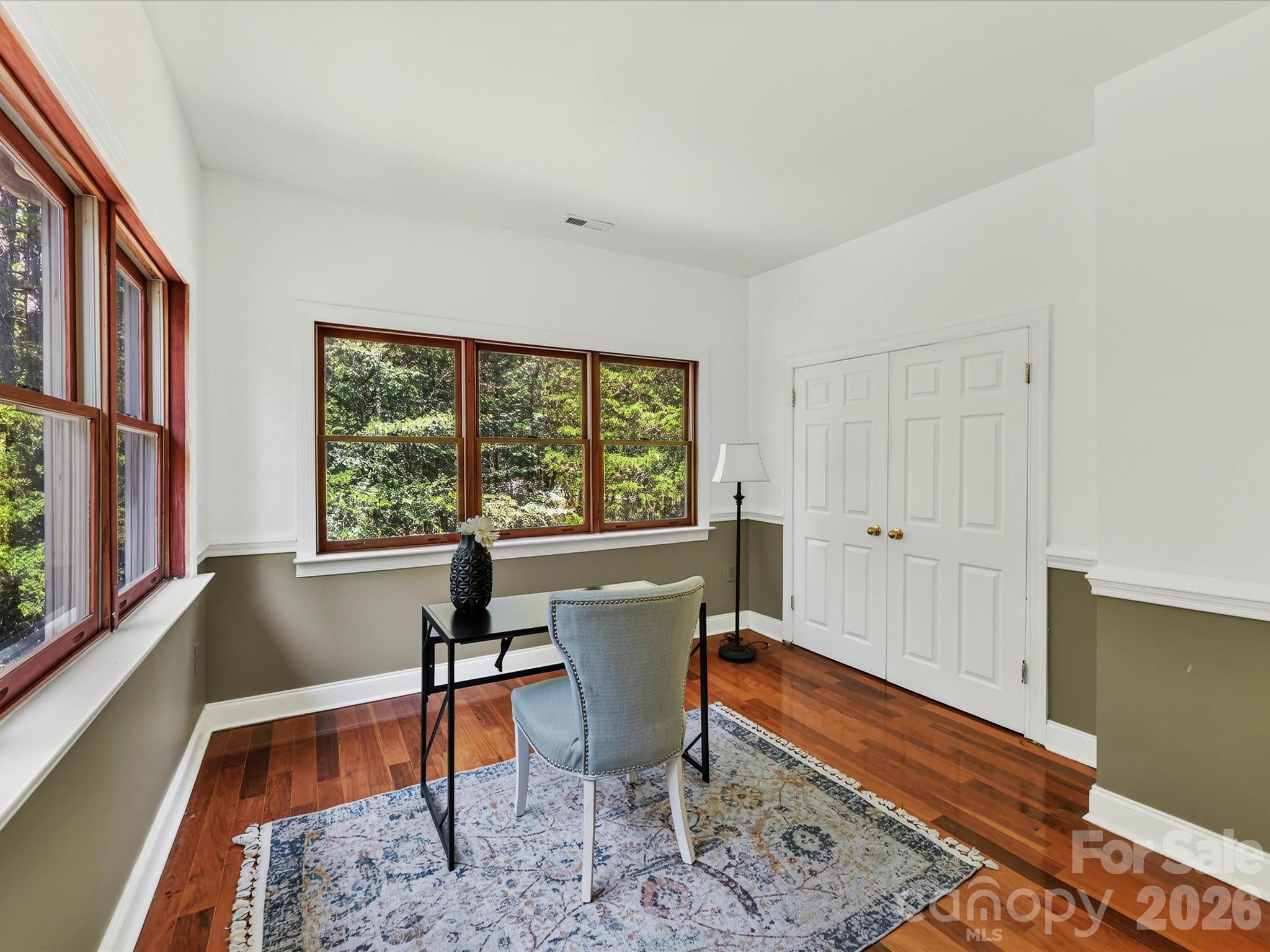 Versatile secondary bedroom with Brazilian hardwood floors, abundant windows, wooded views, and ample closet space is ideal for a bedroom or home office. - 9821 Harvest Lane, Davidson