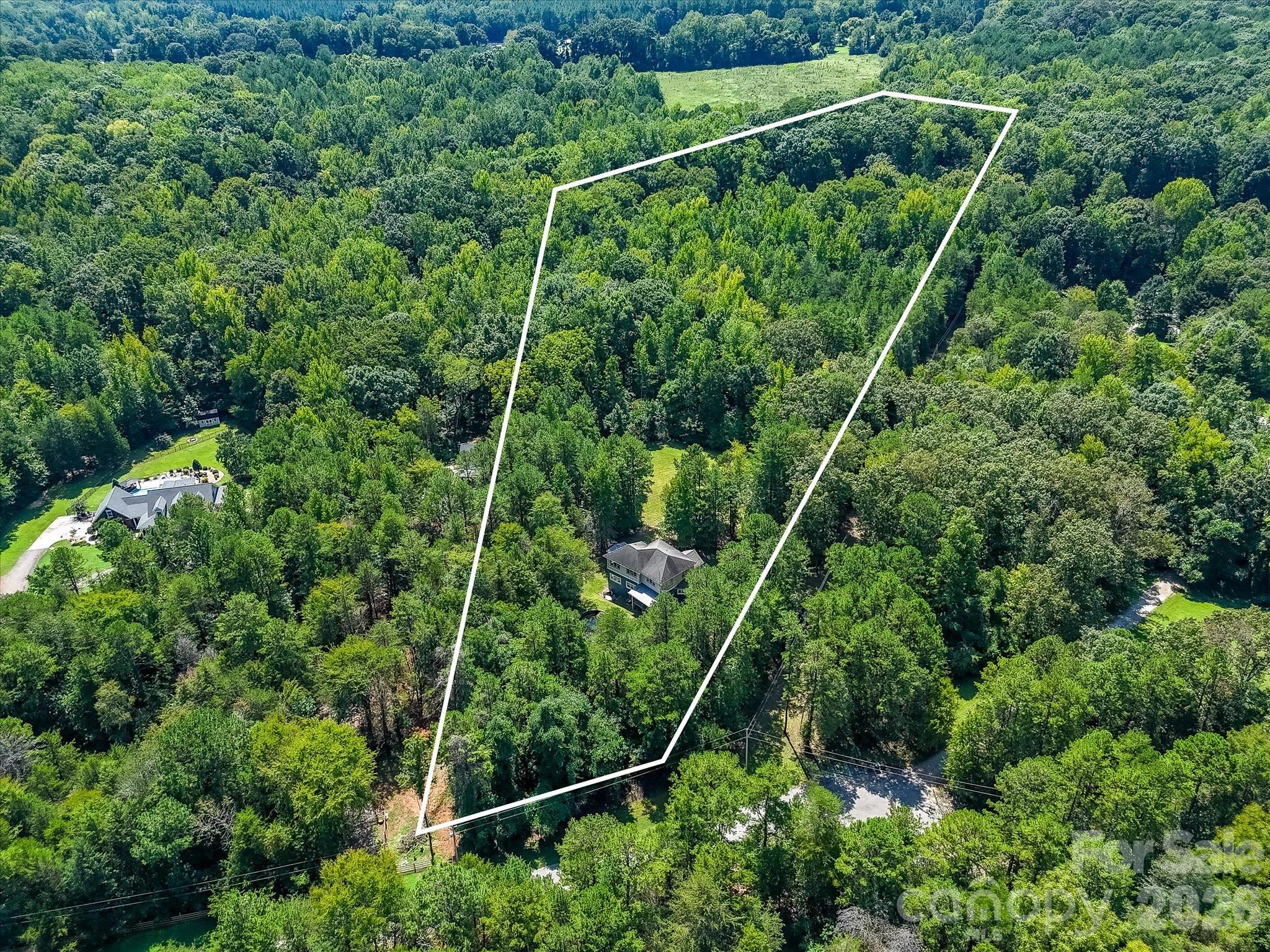 Aerial view showcases the home’s expansive wooded acreage, privacy, and impressive natural surroundings. - 9821 Harvest Lane, Davidson