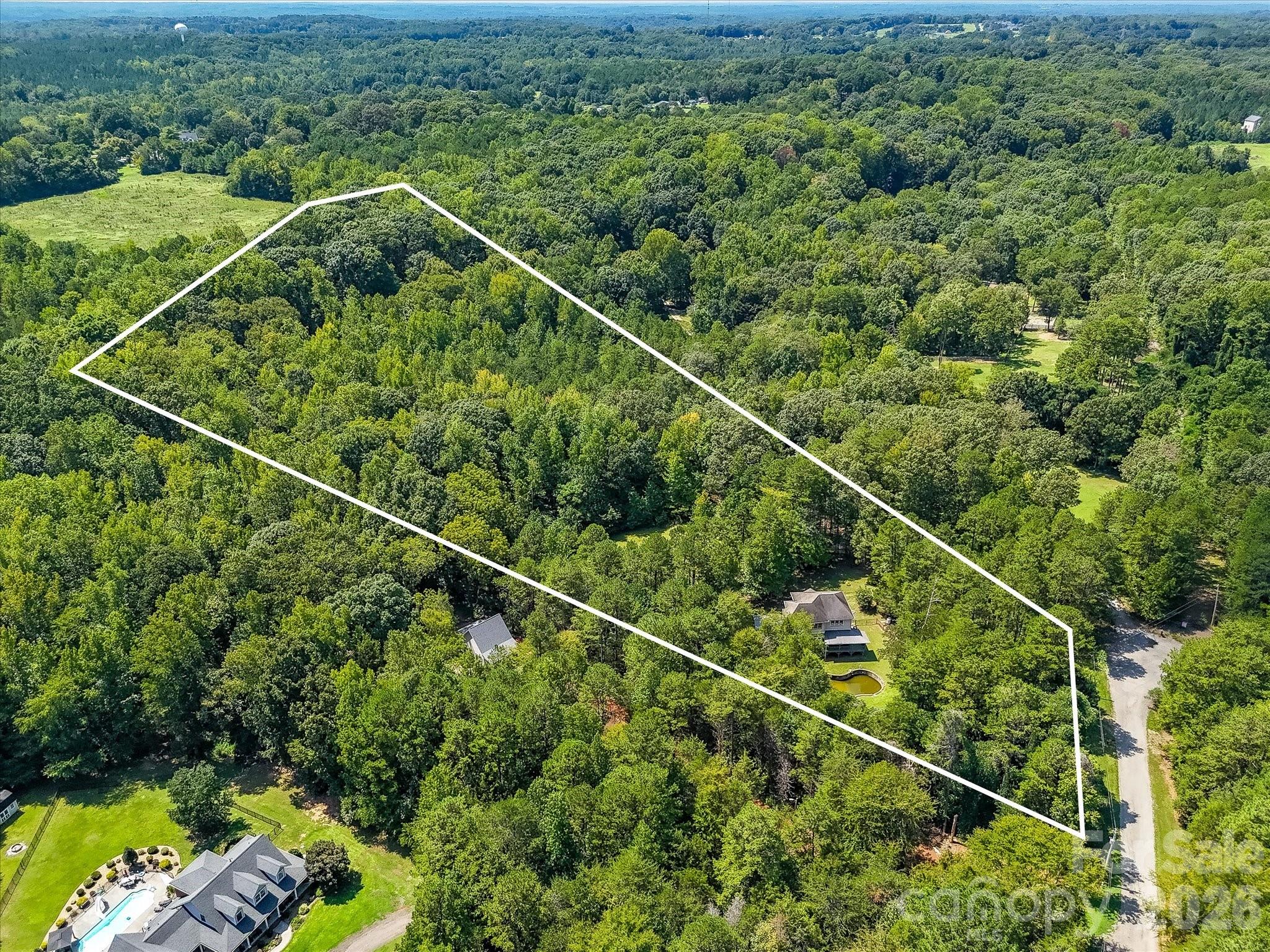 Sweeping aerial view showcases the property’s extensive wooded acreage and secluded setting, offering a rare sense of space and privacy. - 9821 Harvest Lane, Davidson