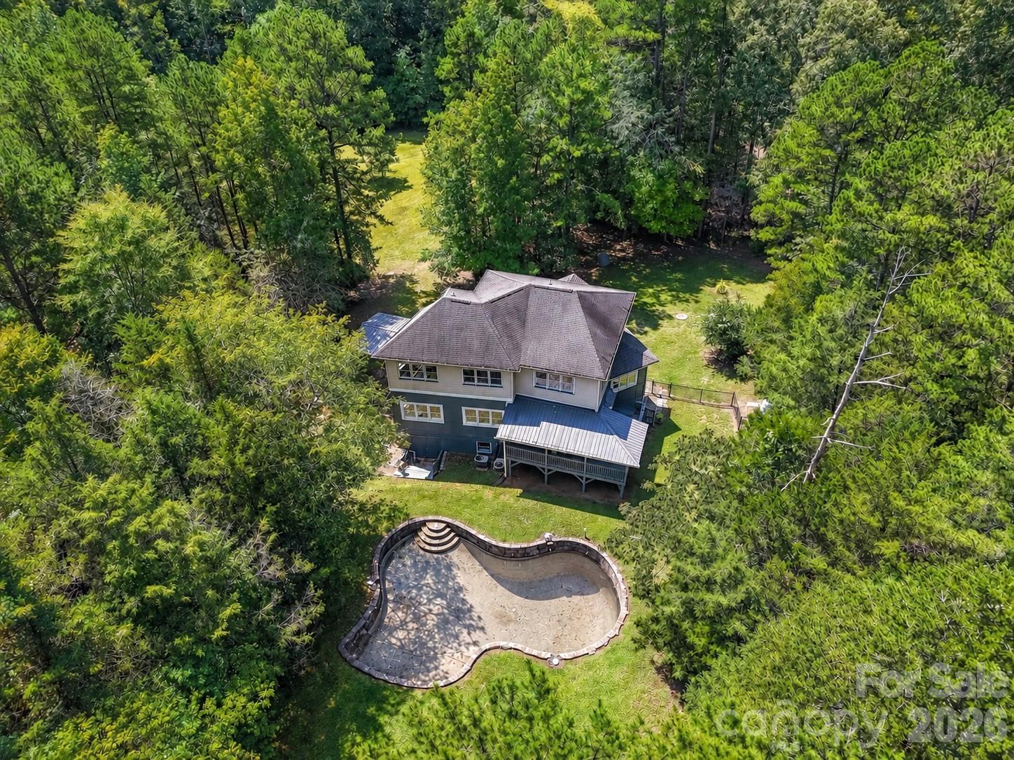 Aerial view showcases the private wooded setting, spacious backyard, and in-ground pool area surrounding the home. - 9821 Harvest Lane, Davidson