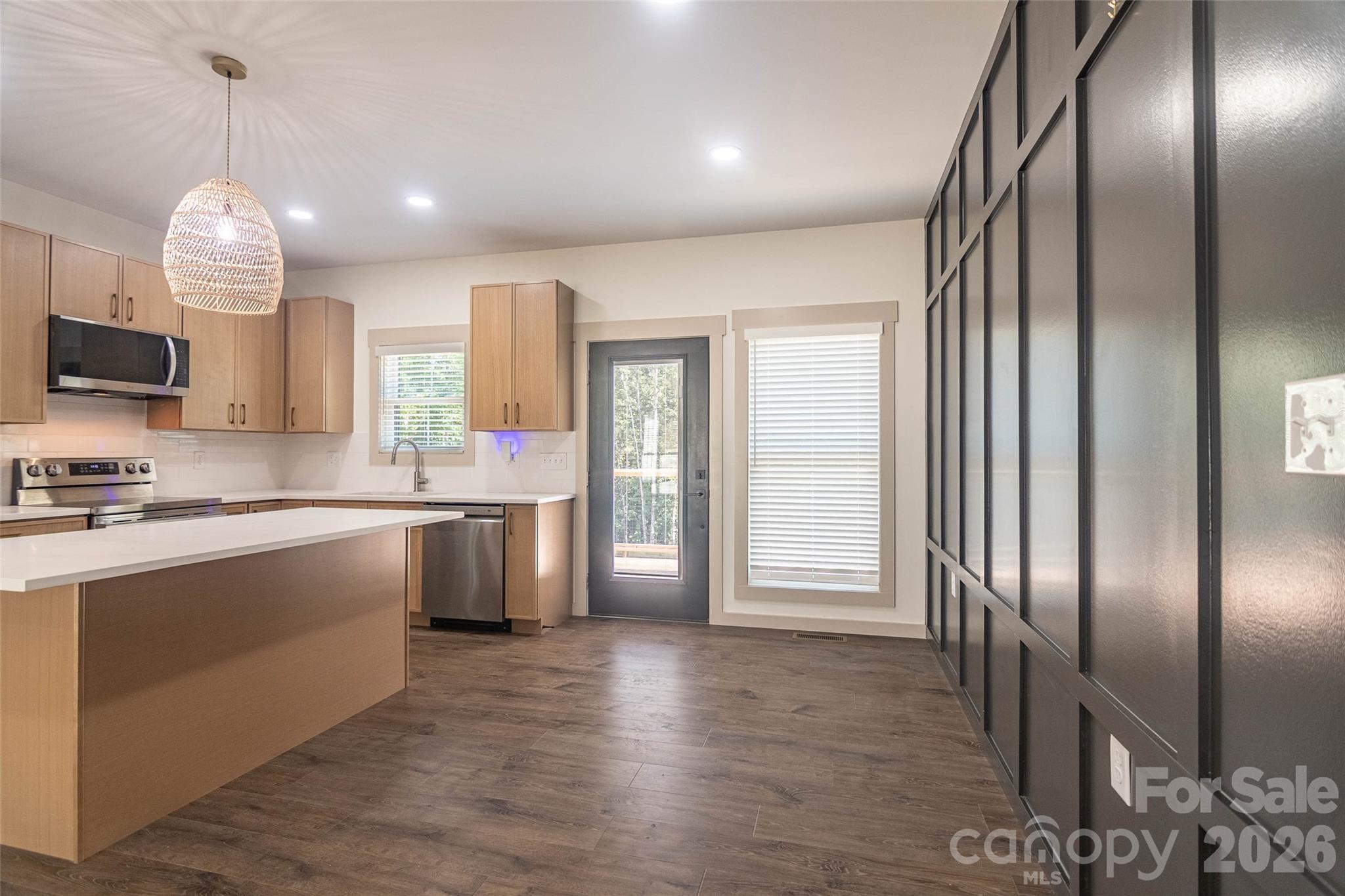 Kitchen and dining area are roomy and continue the lovely floors and wonderful contrasts. Door and windows look out to the rear wooden deck, fenced back yard, and the greenery of the woods beyond! Serene! - 98 Lexxi Lane, Tryon