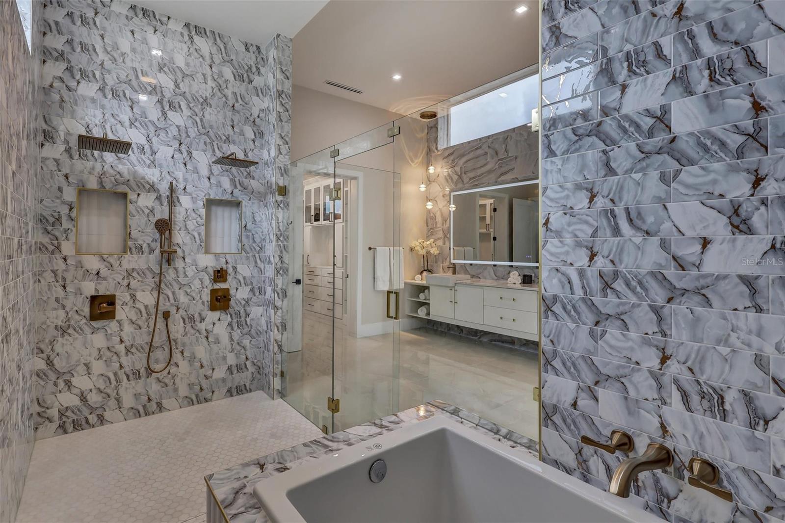 Luxurious soaking tub incorporated within the expansive primary wet room with accompanying built in seat - 1002 COYOTE CREEK WAY, REUNION
