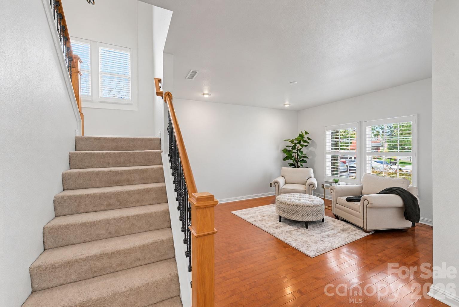 Front staircase featuring warm wood handrails and wrought-iron balusters. - 329 Farm Springs Drive, Mount Holly