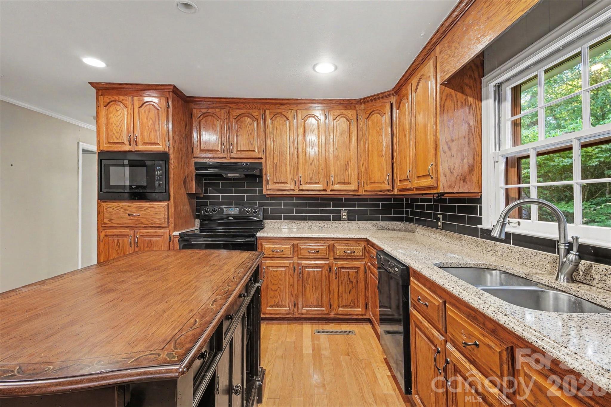 An abundance of Cabinets and Island is accented by the granite countertops and subway tile back splash - 113 Brookshire Avenue, Kannapolis