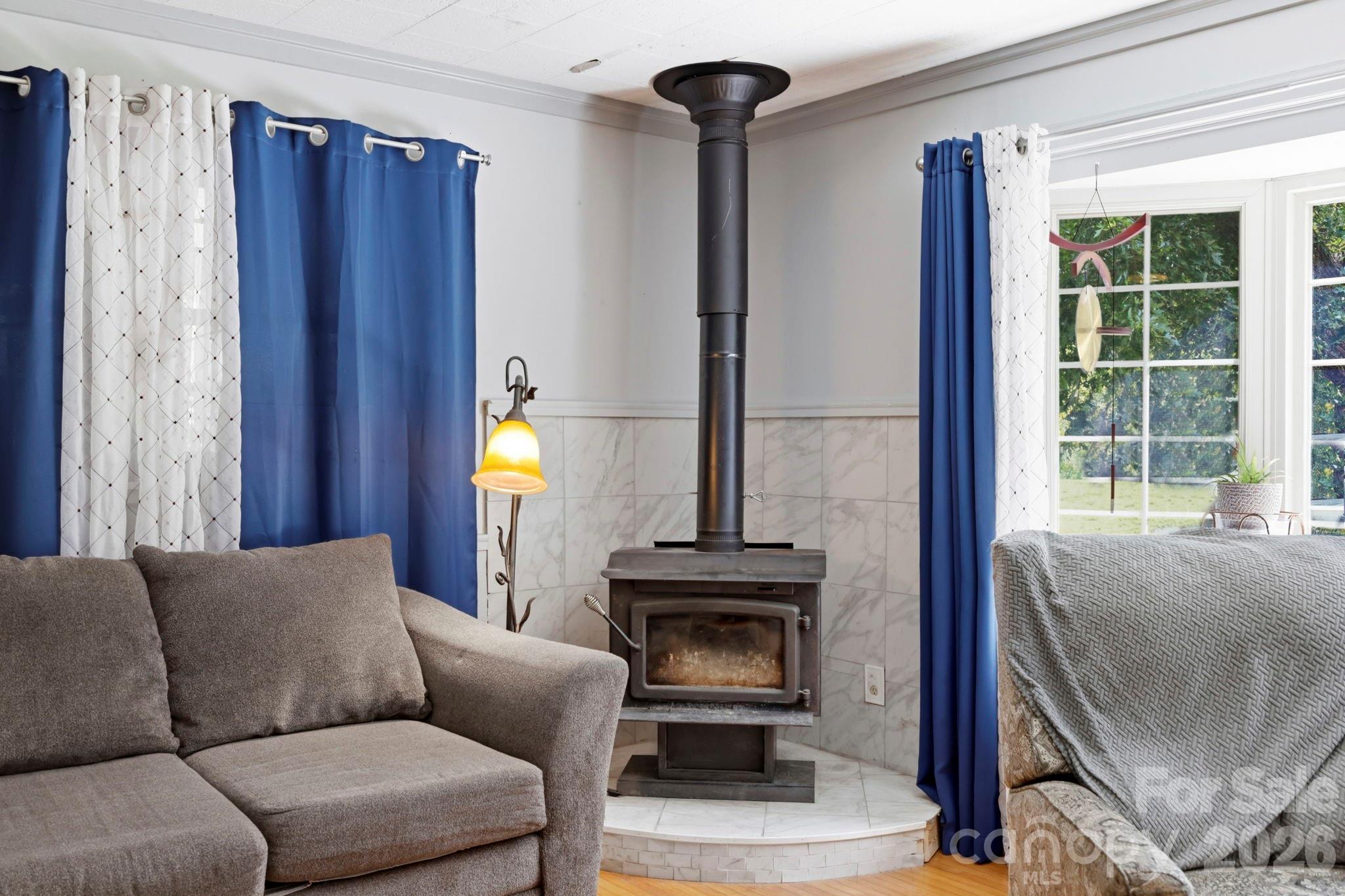 Living room from kitchen doorway, wood burning stove start of bay window - 10687 Cruso Road, Canton